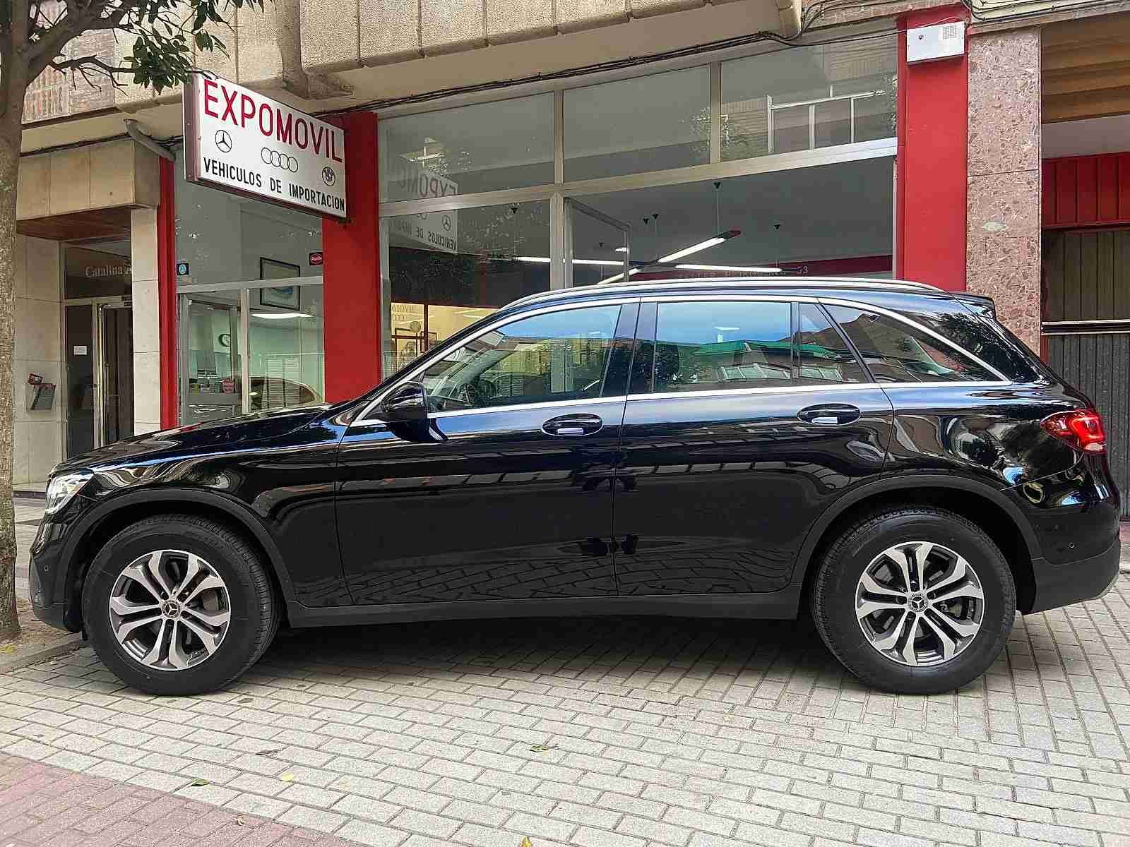 Un todoterreno negro está estacionado frente a un concesionario de automóviles.