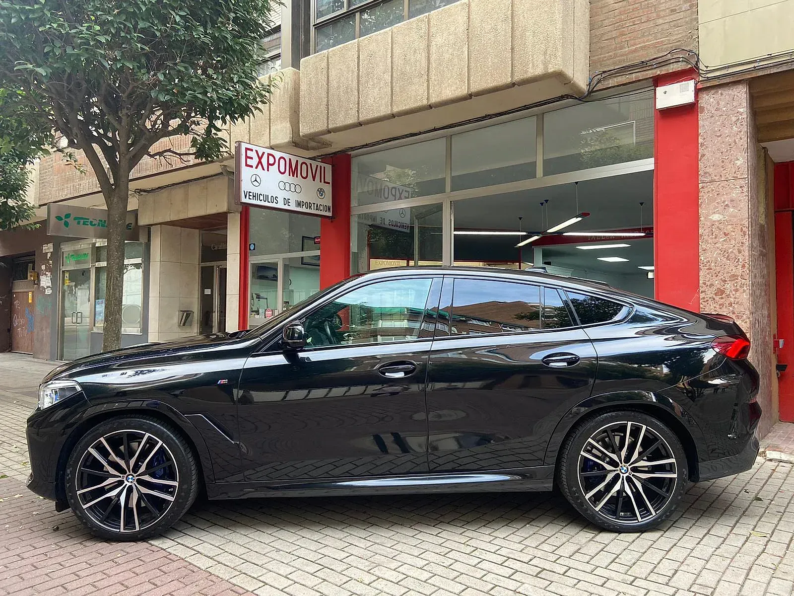 Un coche negro está aparcado delante de un edificio.