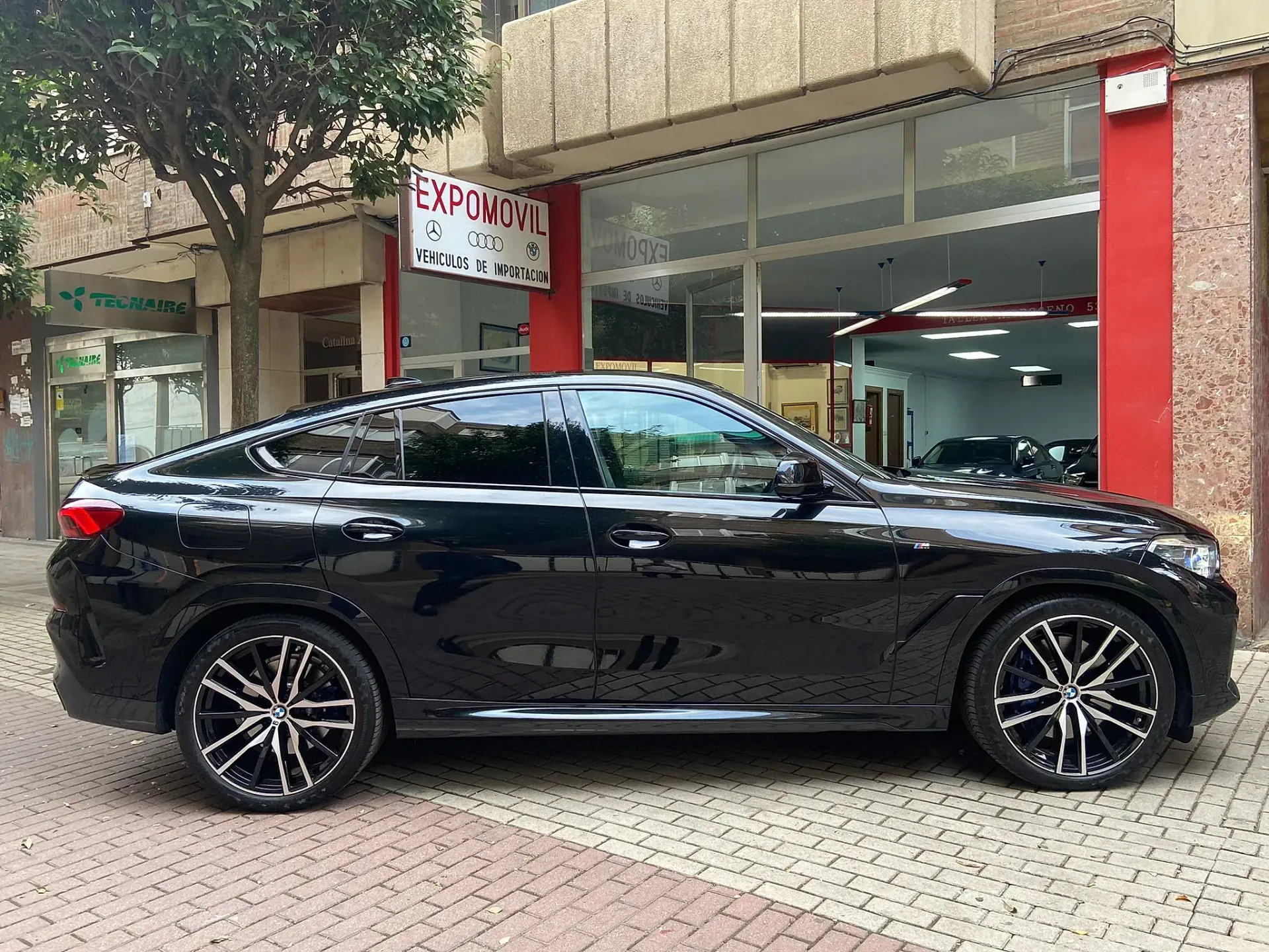 Un coche negro está aparcado delante de un concesionario de automóviles.