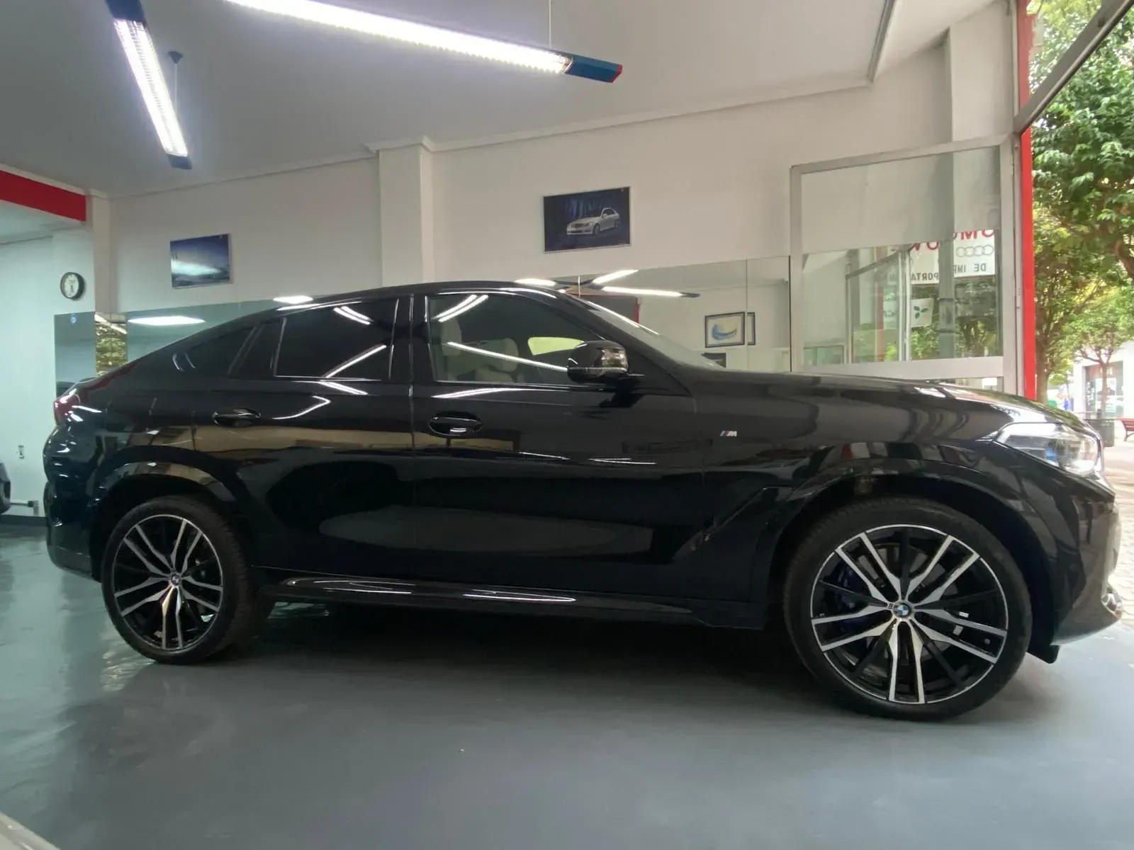 Un BMW X6 negro está estacionado en una sala de exposición.