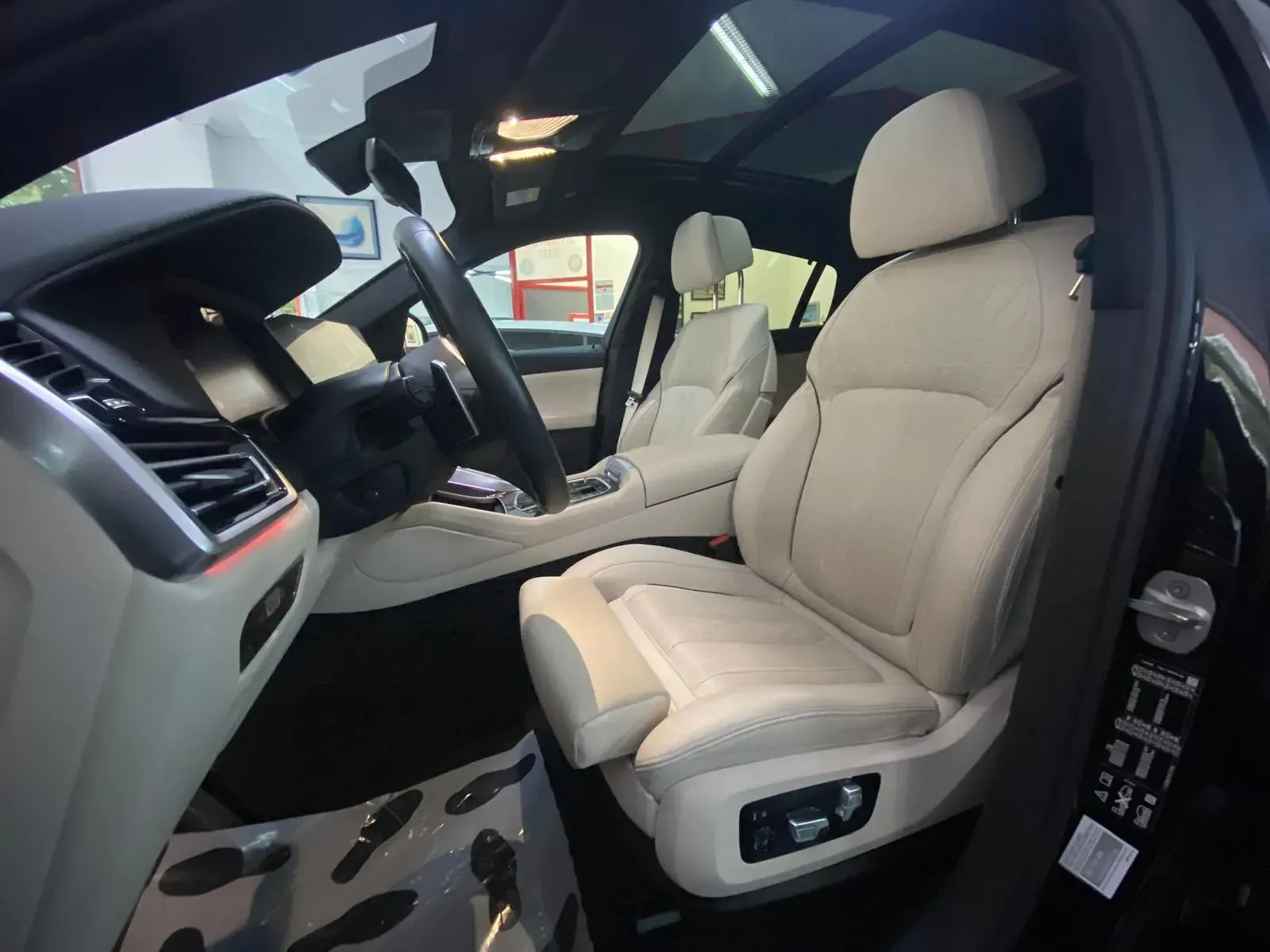 El interior de un coche negro con asientos blancos y un volante.