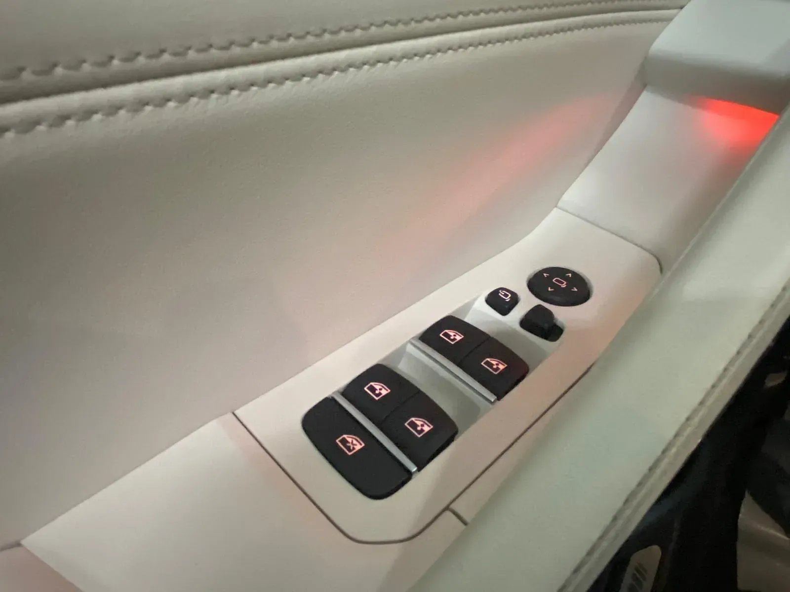 Un primer plano del control de la puerta de un automóvil con una luz roja detrás.