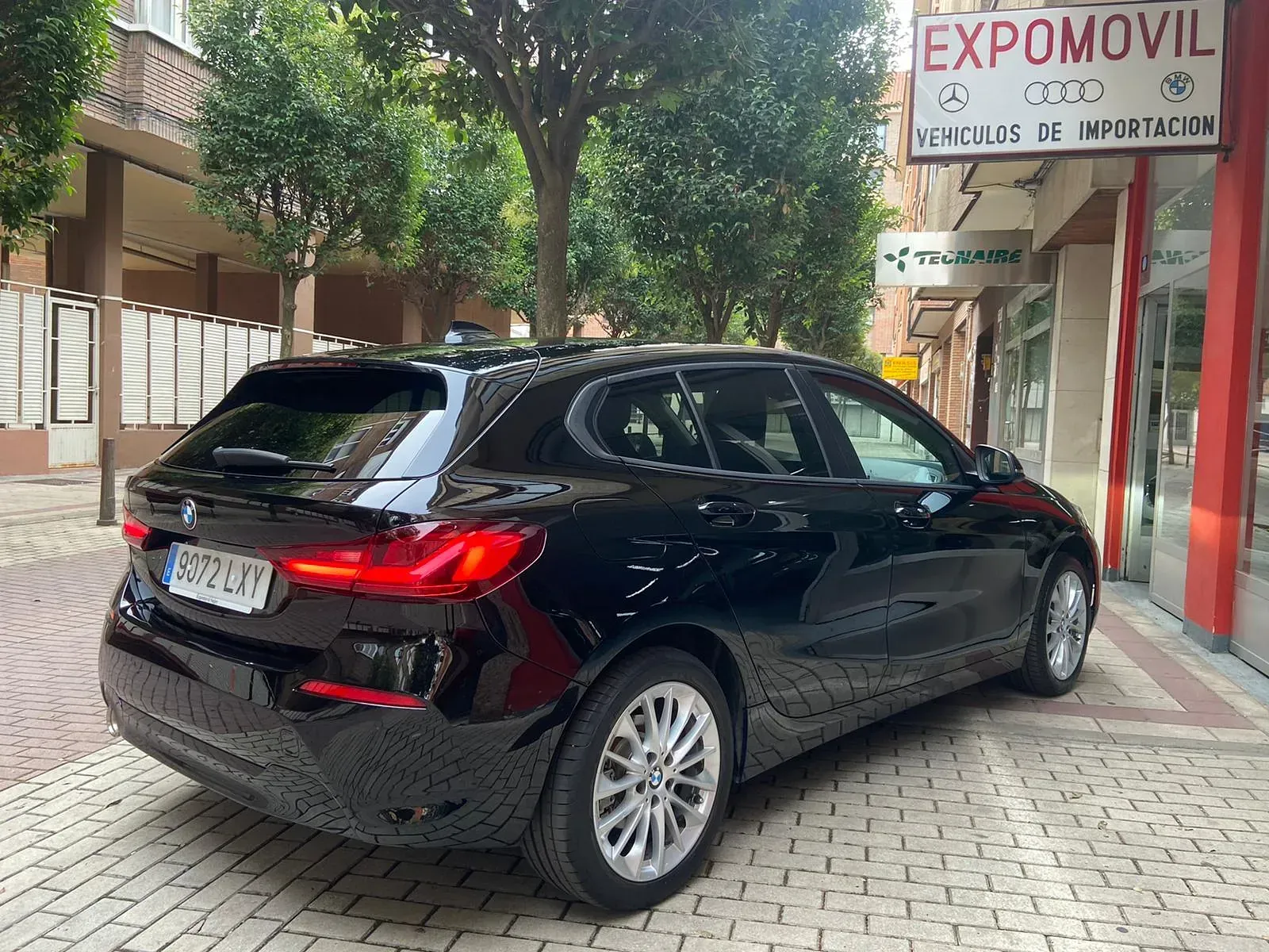 Un coche negro está estacionado frente a un edificio con un cartel que dice expomovil.