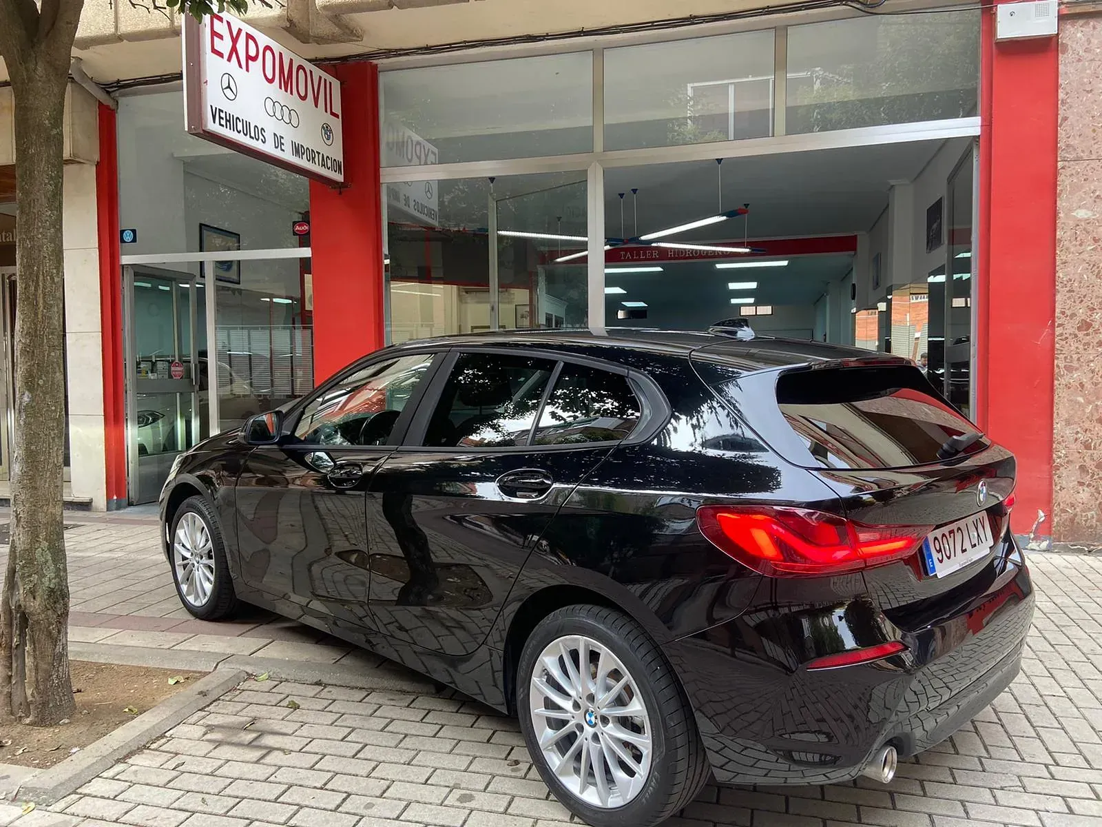 Un coche negro está aparcado delante de un concesionario de automóviles.