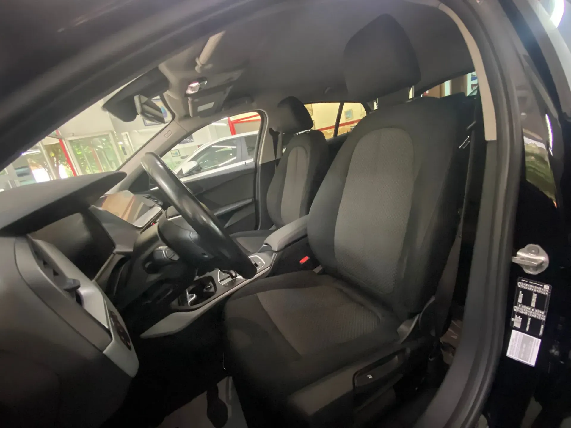 El interior de un coche negro con volante y asientos.