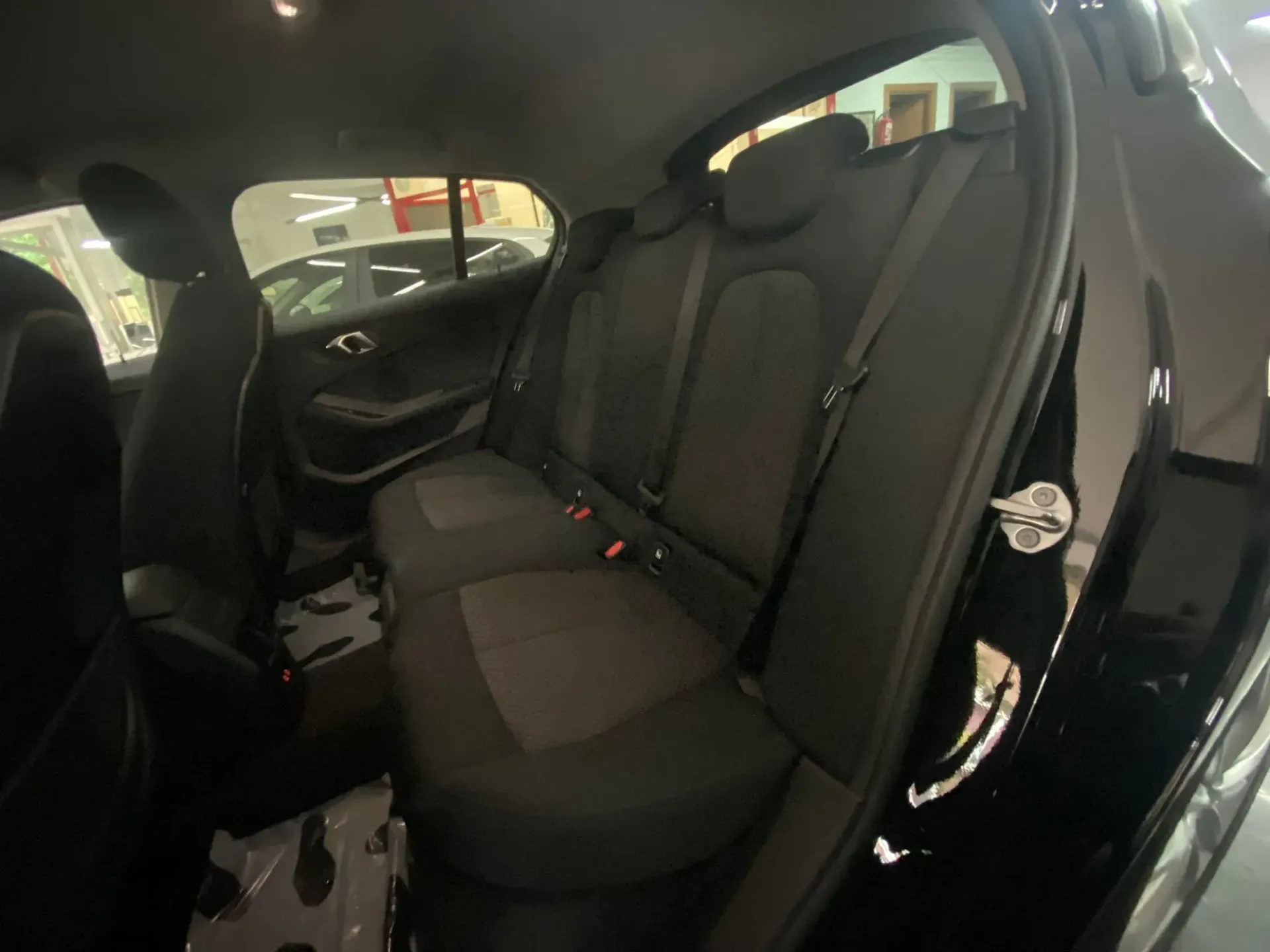 Se muestra el asiento trasero de un automóvil negro en una sala de exposición.