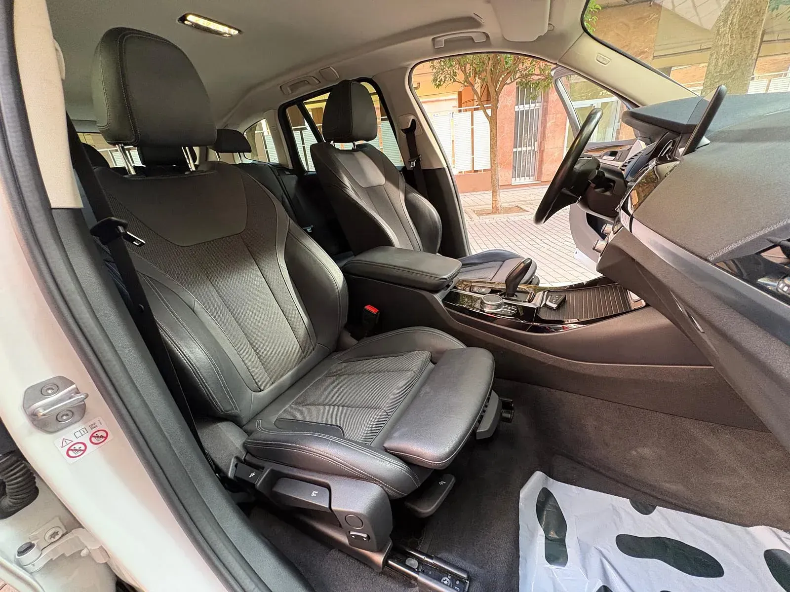 El interior de un coche blanco con asientos de cuero negro y un volante.