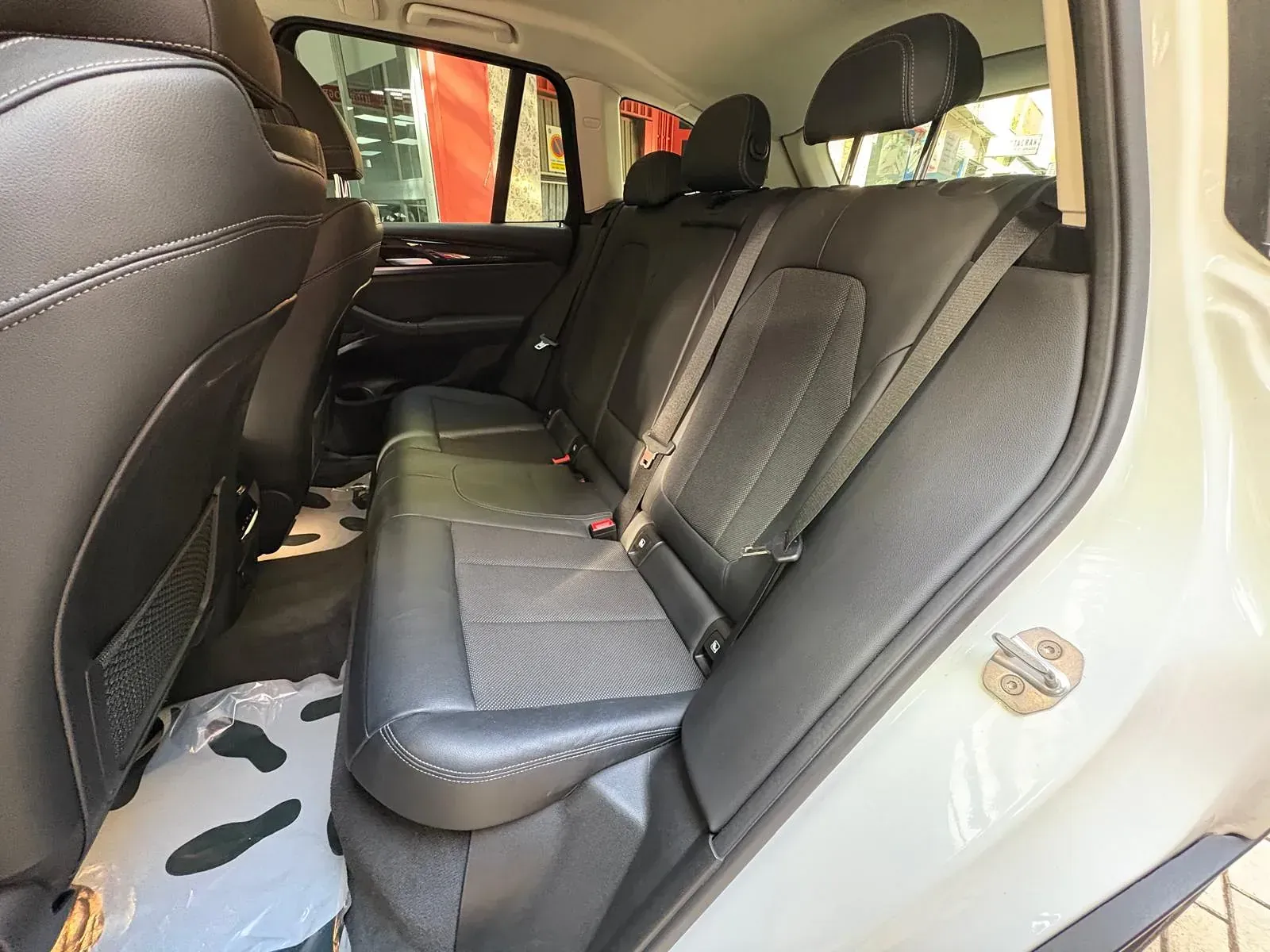 El asiento trasero de un coche blanco con asientos de cuero negro.
