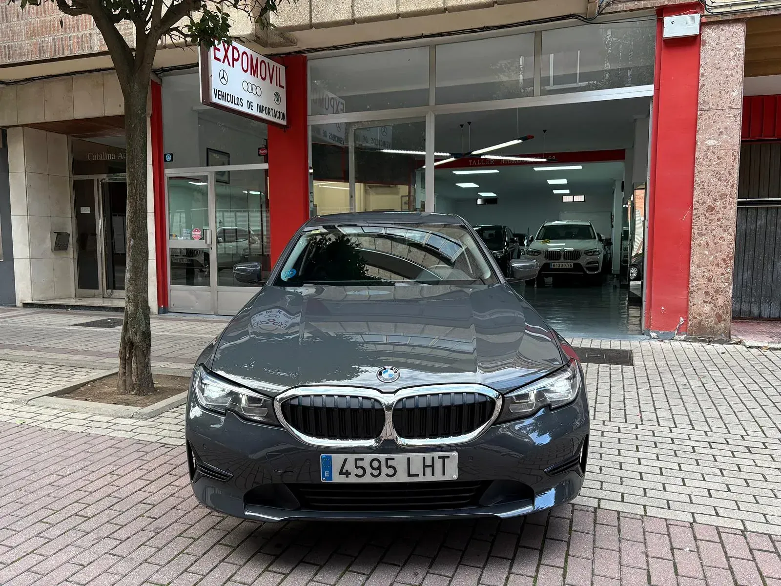 Un BMW está aparcado delante de un concesionario de coches.
