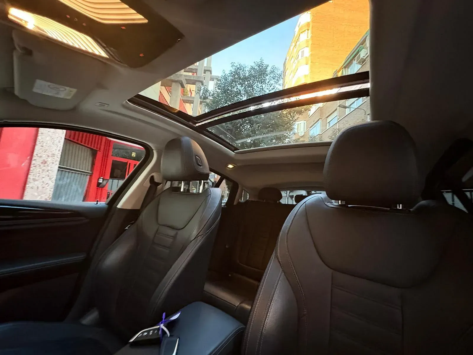 Un coche con techo solar está estacionado delante de un edificio.