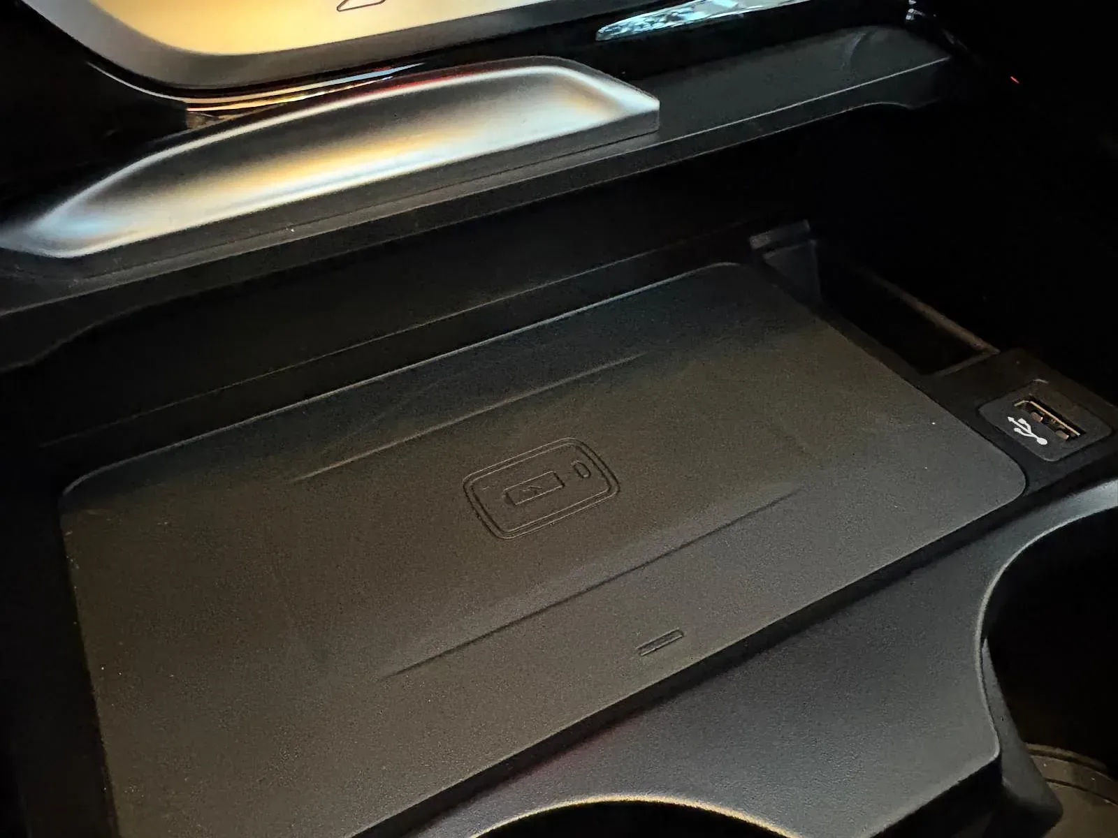 Un cargador inalámbrico está ubicado debajo de un portavasos en un automóvil.