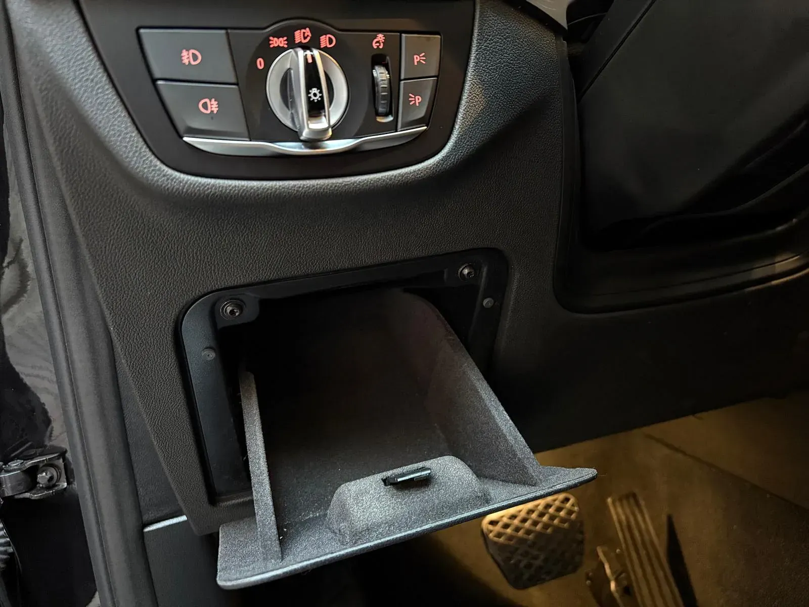 Un primer plano del salpicadero de un coche con la guantera abierta.