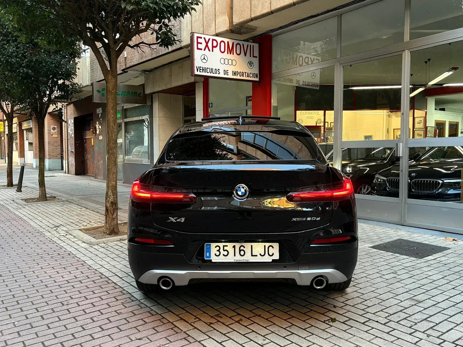 Un coche negro está aparcado delante de un concesionario de automóviles.