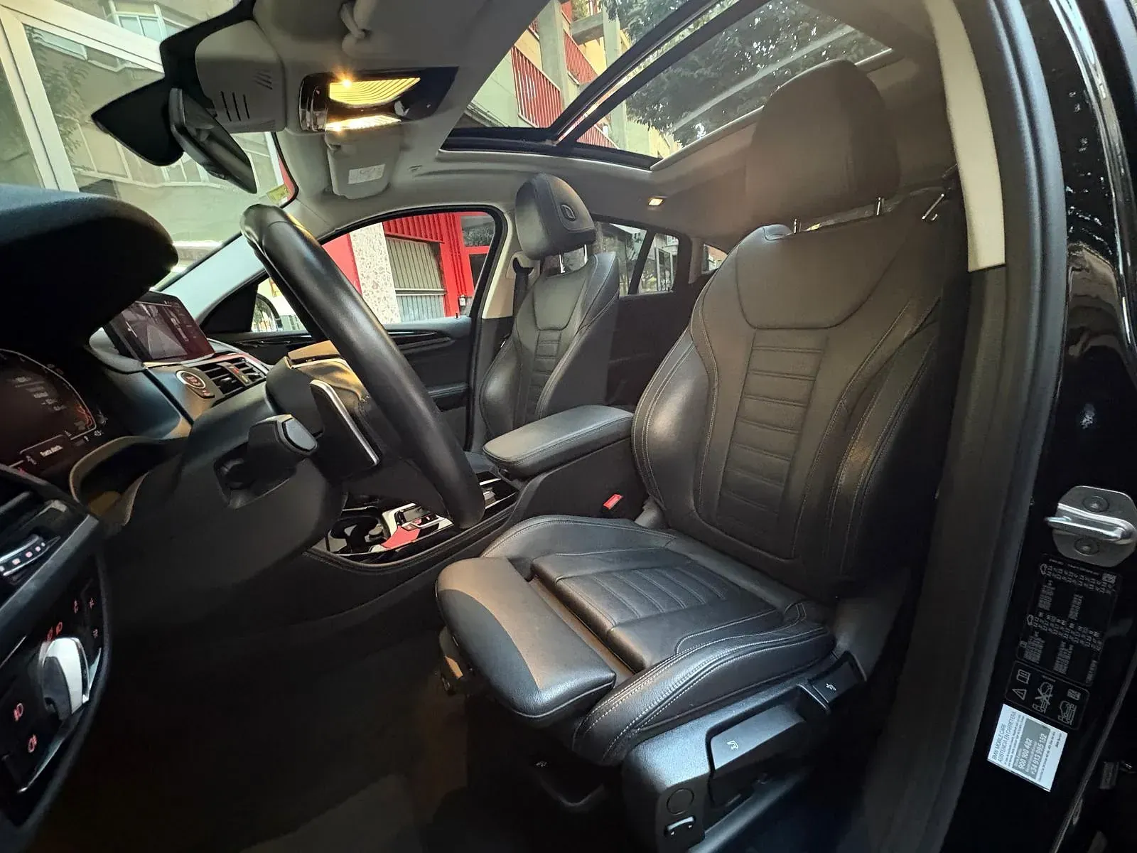 El interior de un coche negro con asientos de cuero y techo corredizo.