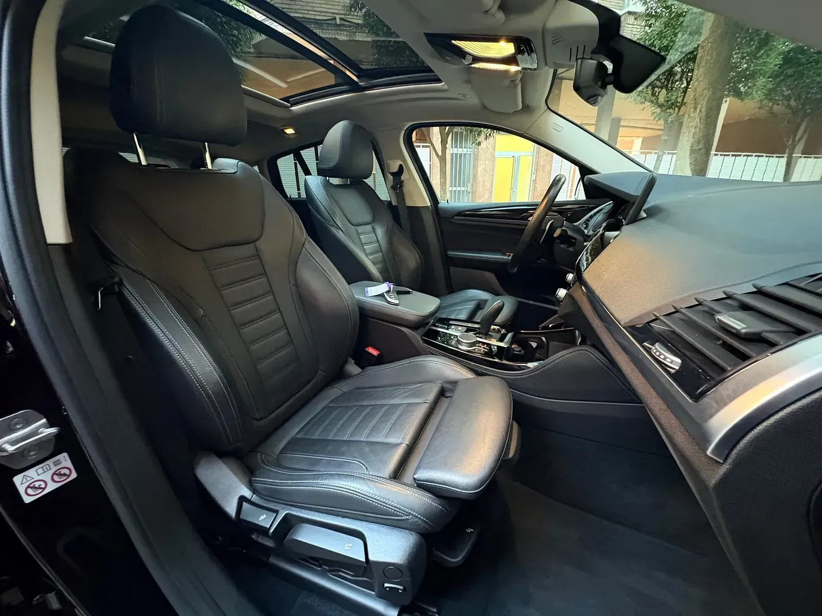 El interior de un coche negro con techo corredizo y asientos de cuero.