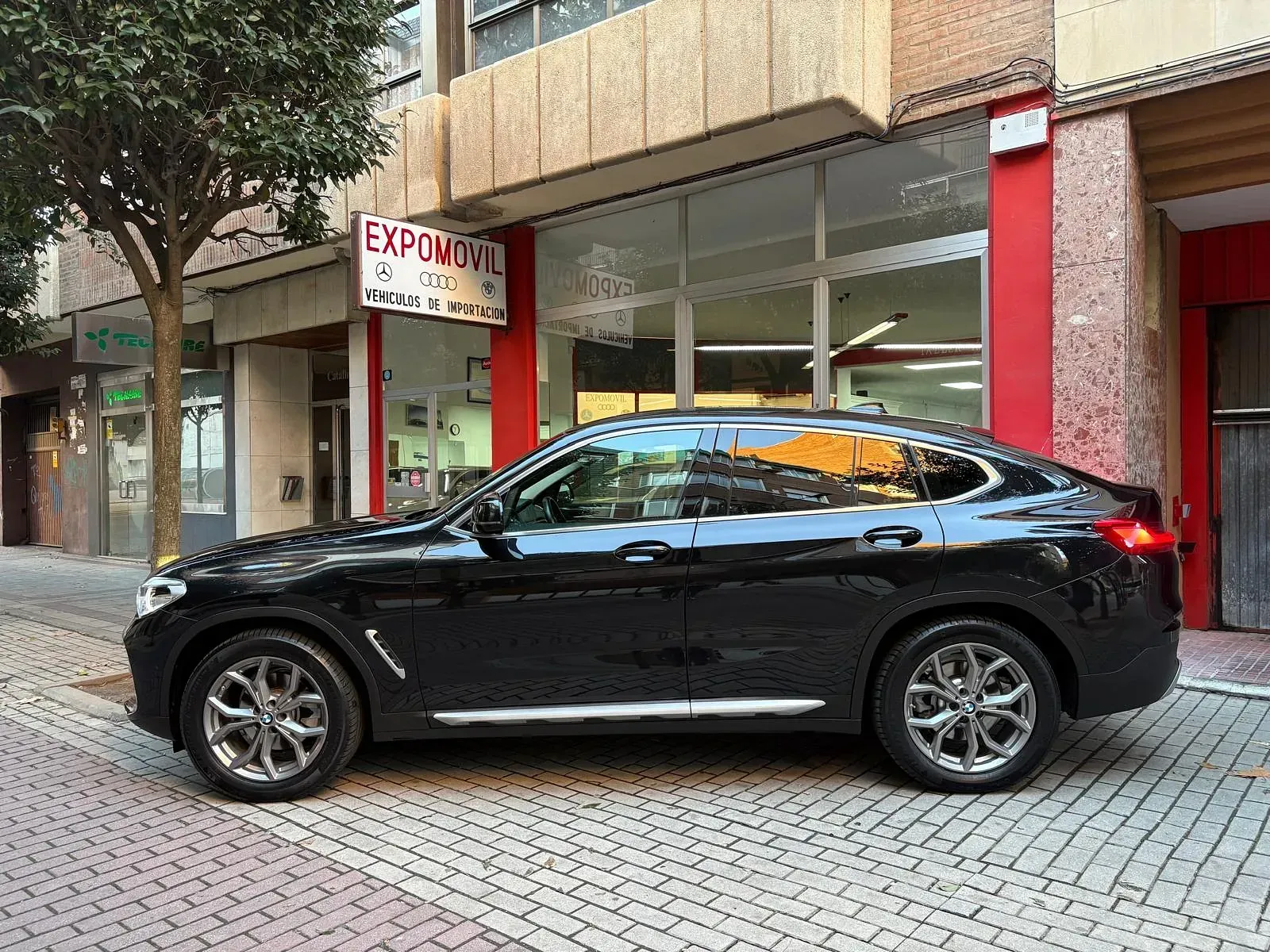 Un coche negro está aparcado delante de un edificio.