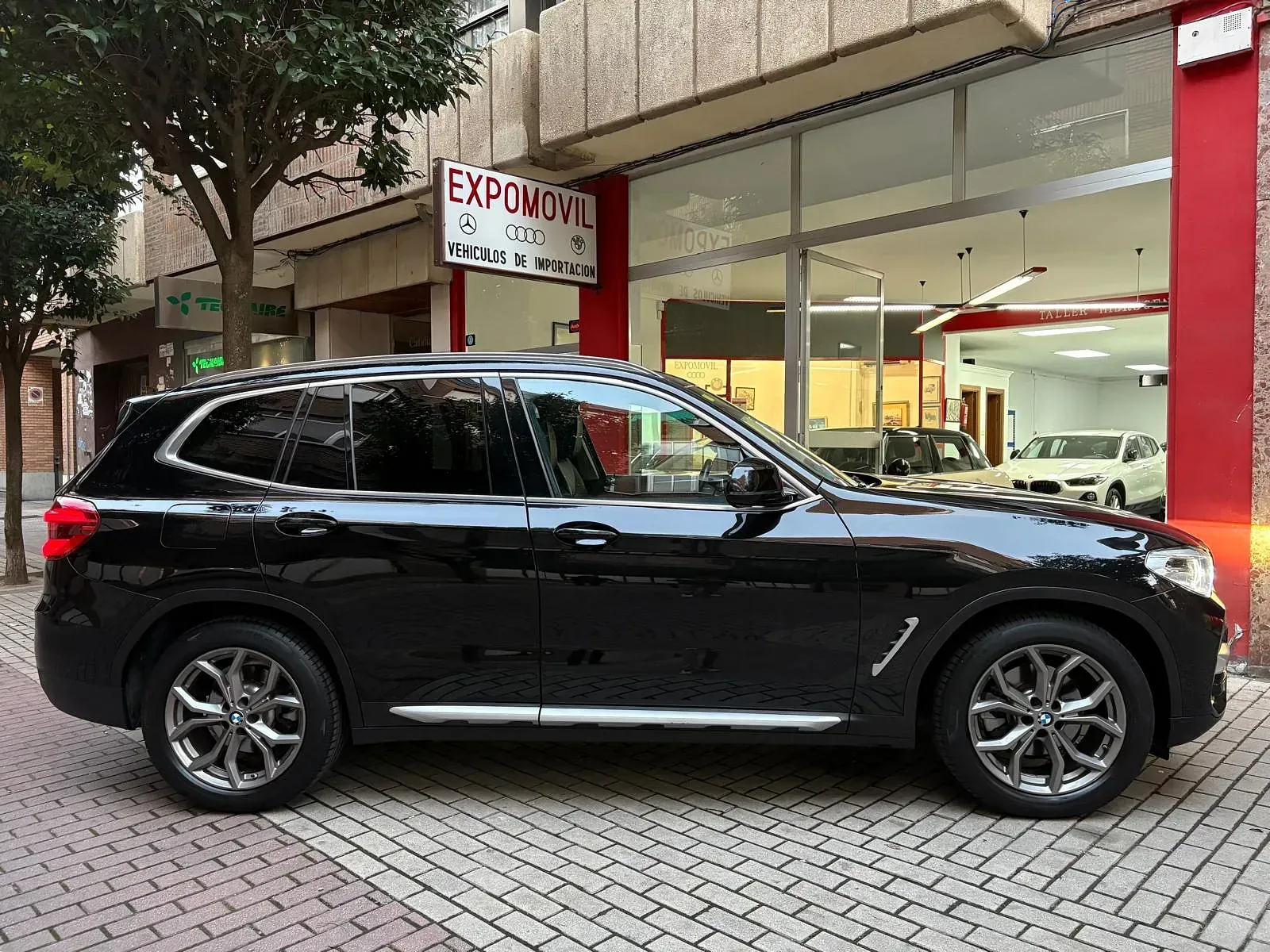 Un todoterreno negro está estacionado frente a un concesionario de automóviles.