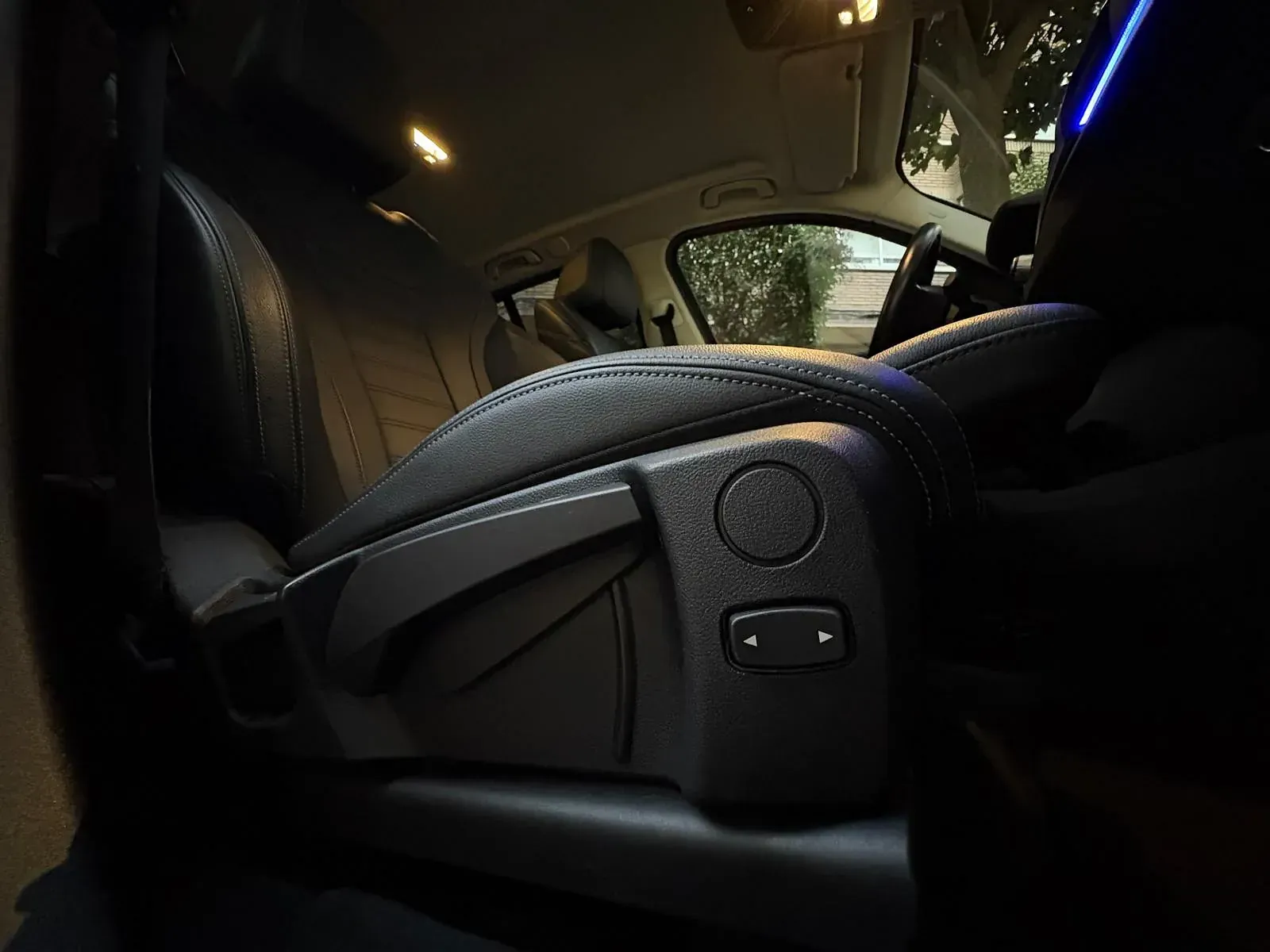 Un primer plano de un asiento de automóvil con un volante al fondo.