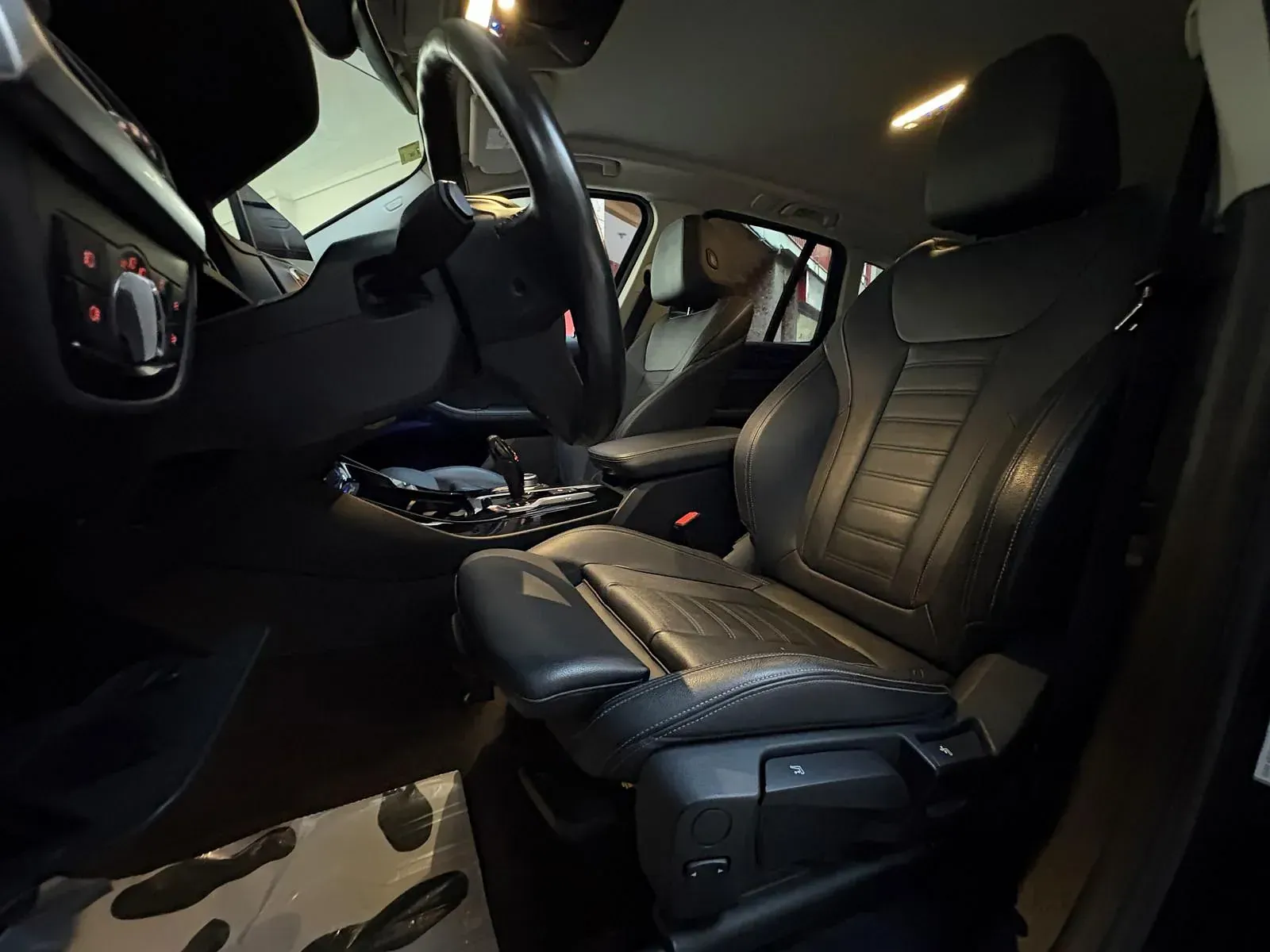 El interior de un coche con asientos de cuero negro y un volante.