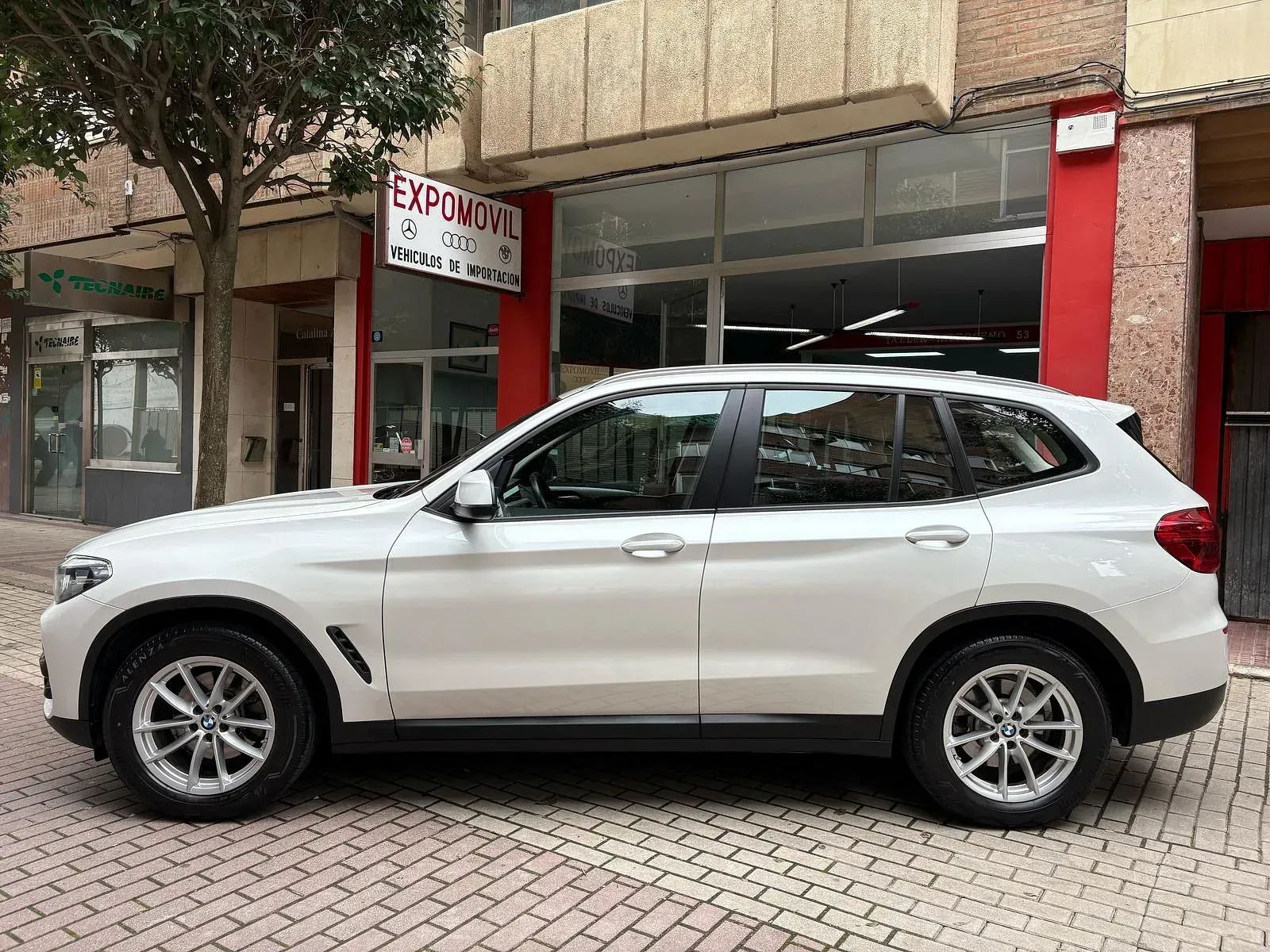 Un todoterreno blanco está estacionado frente a un edificio.