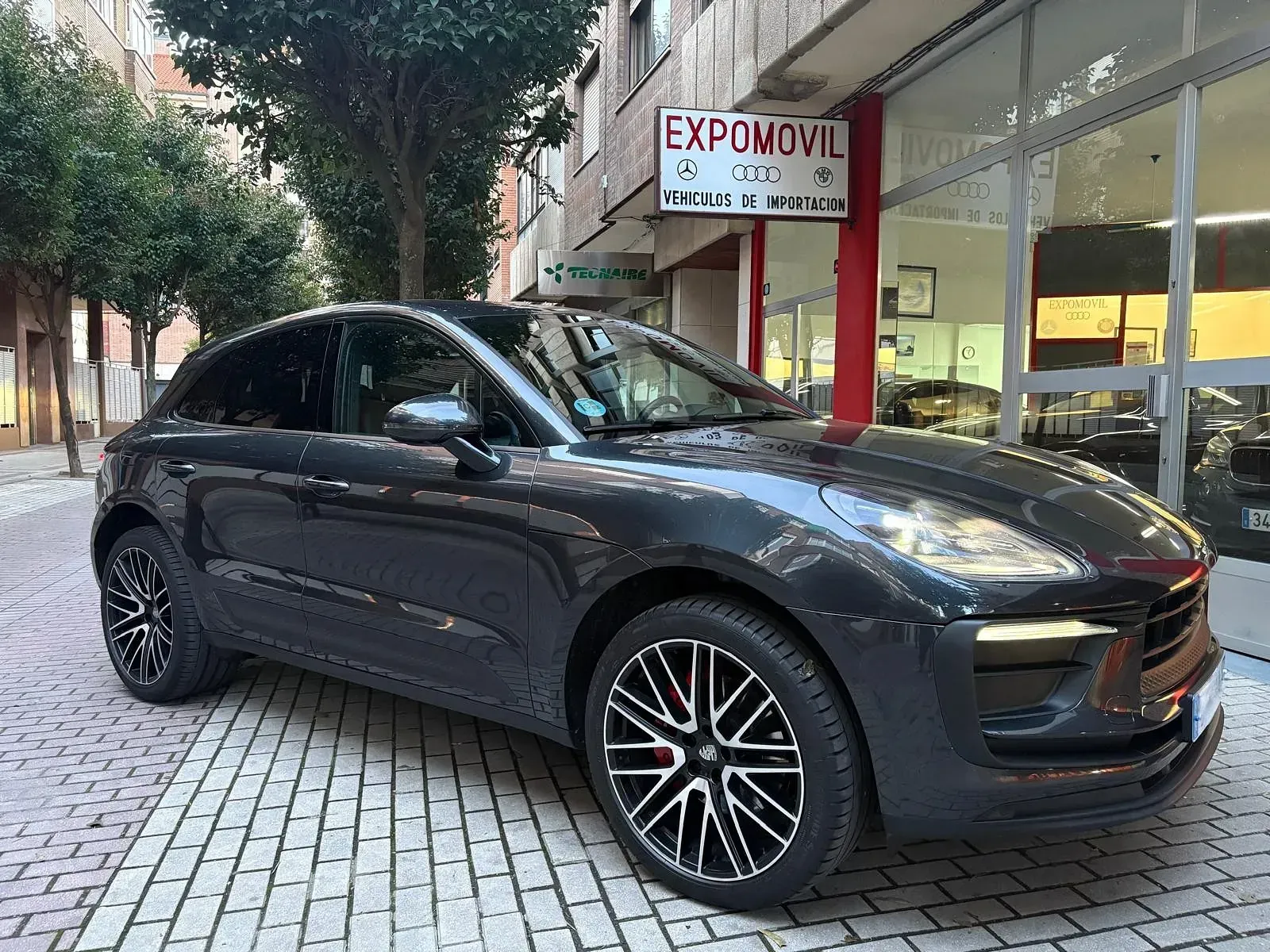 Un Porsche Macan está estacionado frente a un concesionario de automóviles.