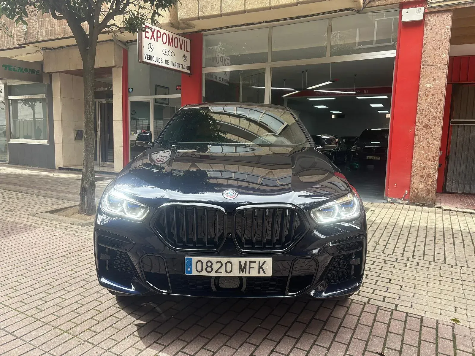 Un BMW negro está estacionado frente a un concesionario de automóviles.