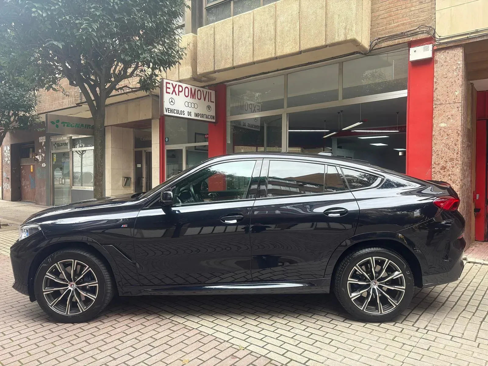 Un coche negro está aparcado delante de un edificio.