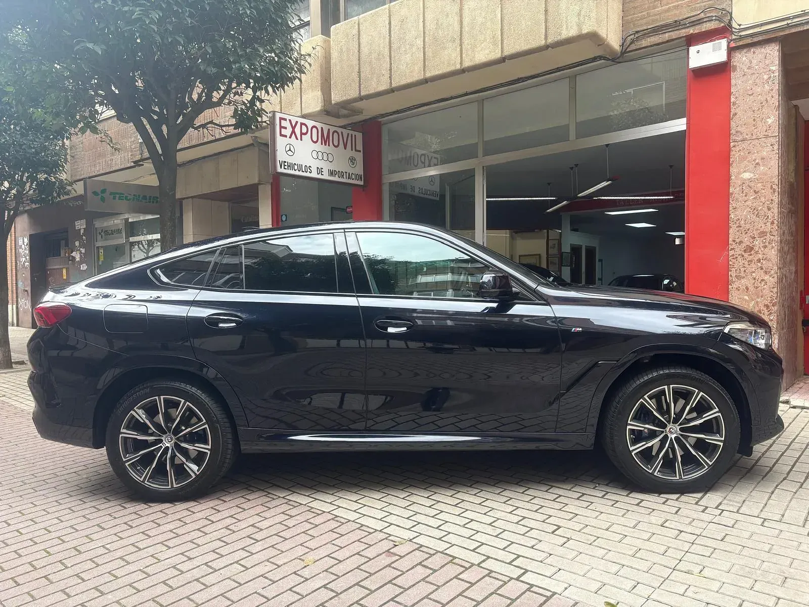 Un coche negro está aparcado delante de un edificio.