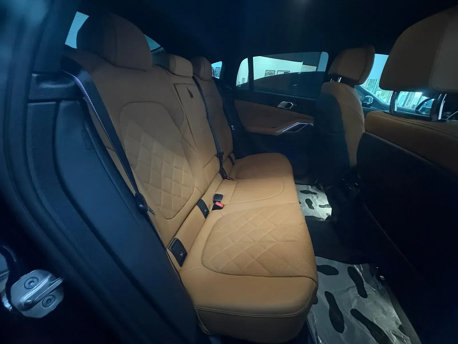 El asiento trasero de un coche con asientos de cuero marrón.