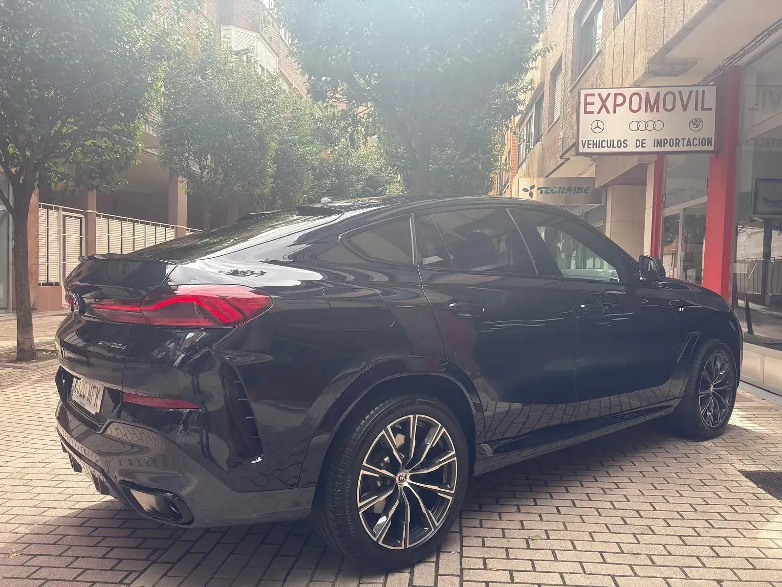 Un coche negro está estacionado frente a un edificio que dice expomovil