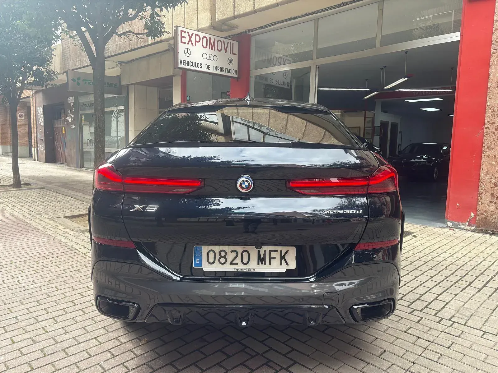 Un automóvil negro con matrícula que dice 0820 mfk está estacionado frente a un edificio.