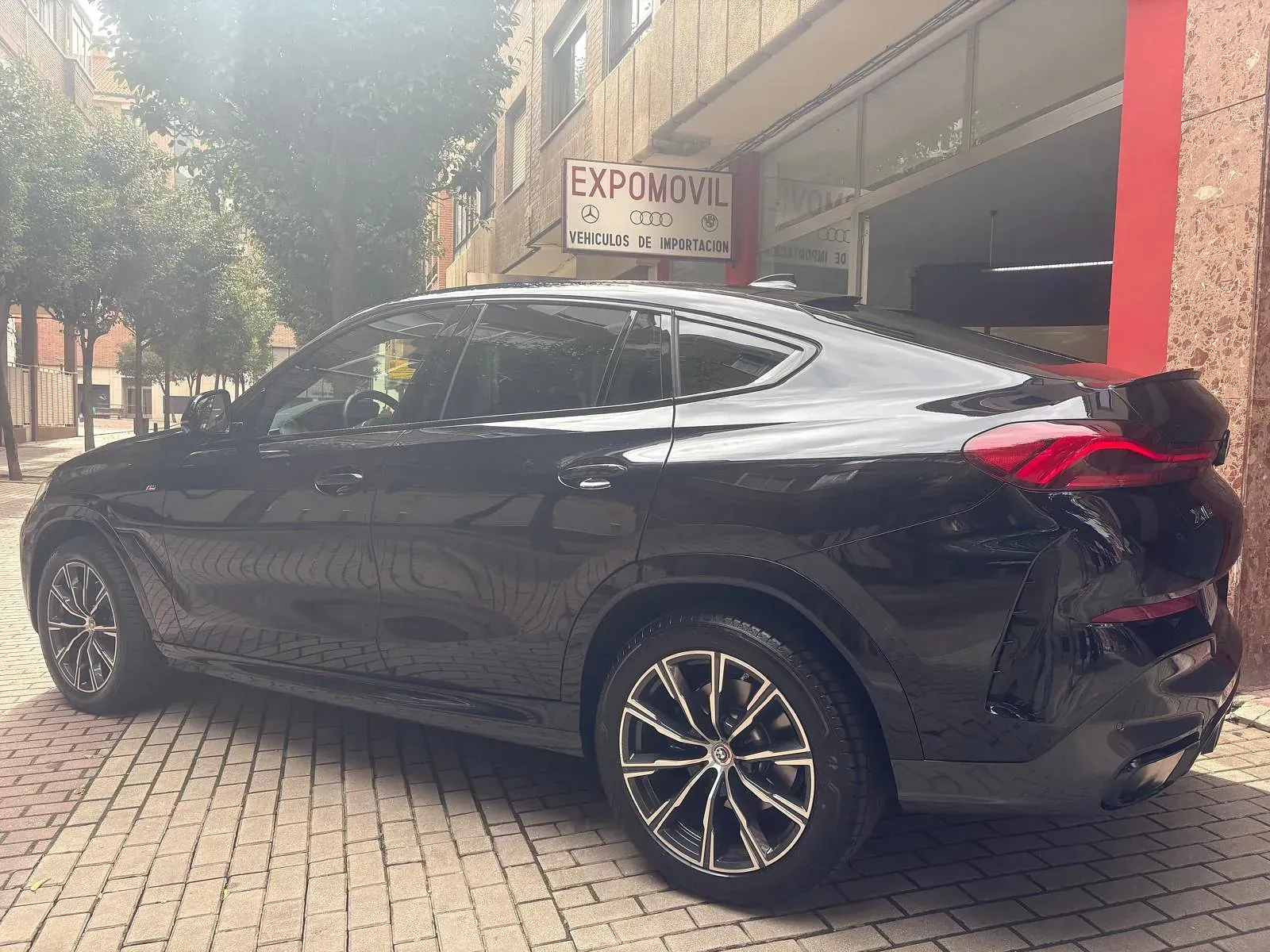 Un coche negro está estacionado frente a un edificio que dice expomovil.