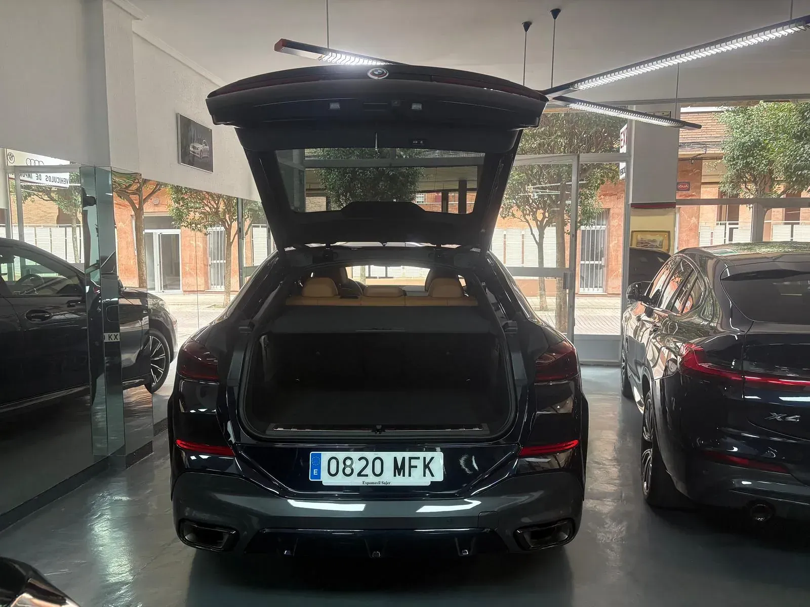 Un coche negro con el maletero abierto está aparcado en un garaje.