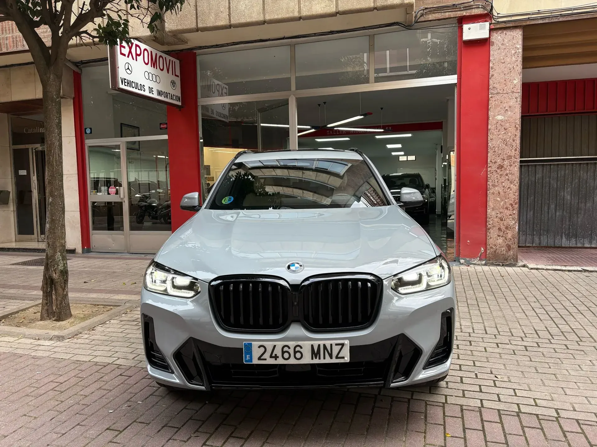 Un BMW X3 está estacionado frente a un concesionario de automóviles.