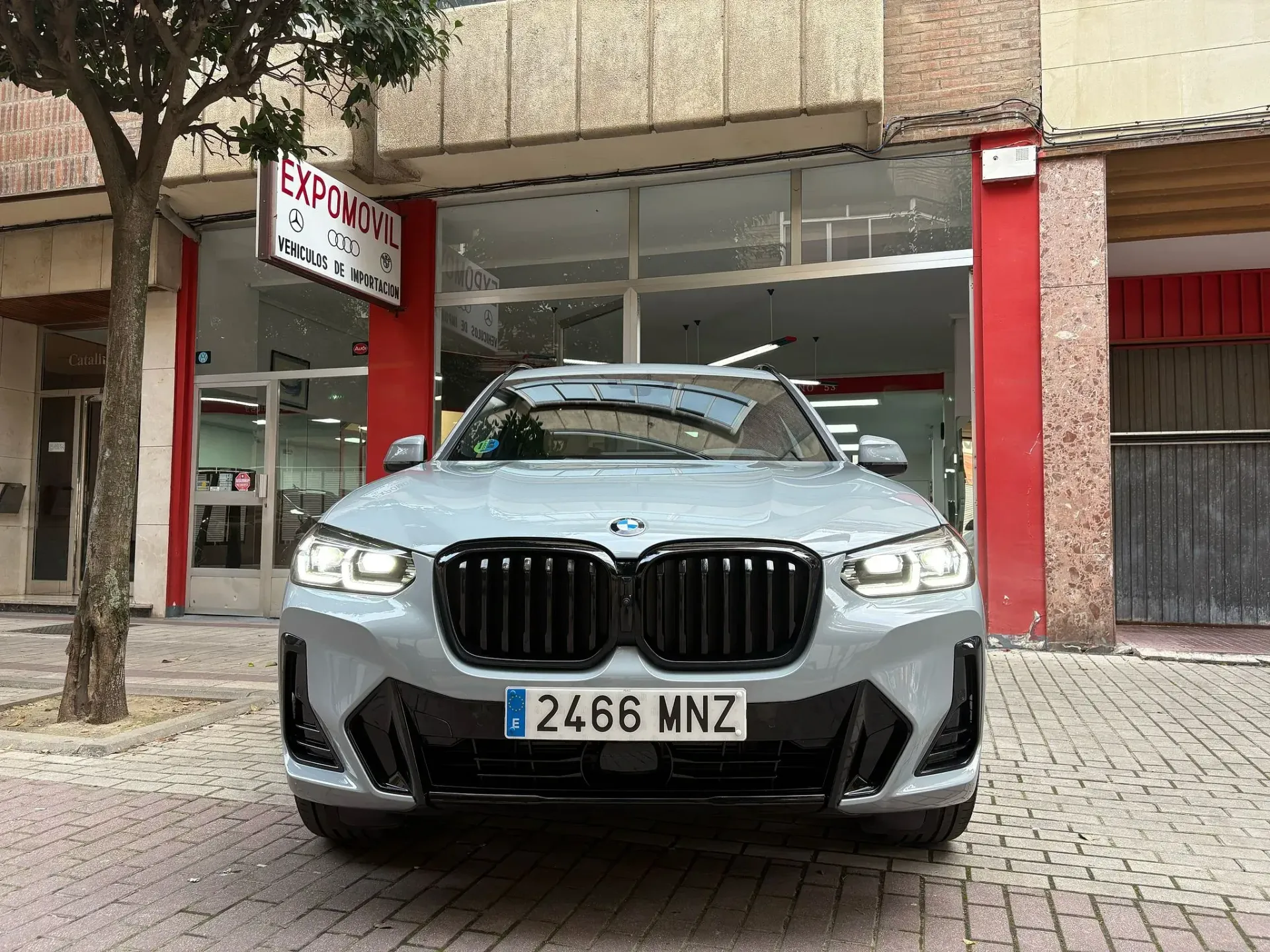 Un BMW gris está estacionado frente a un edificio.