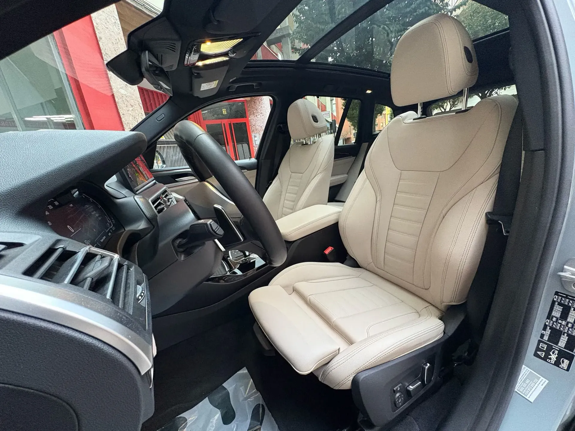 El interior de un coche con asientos blancos y techo corredizo.