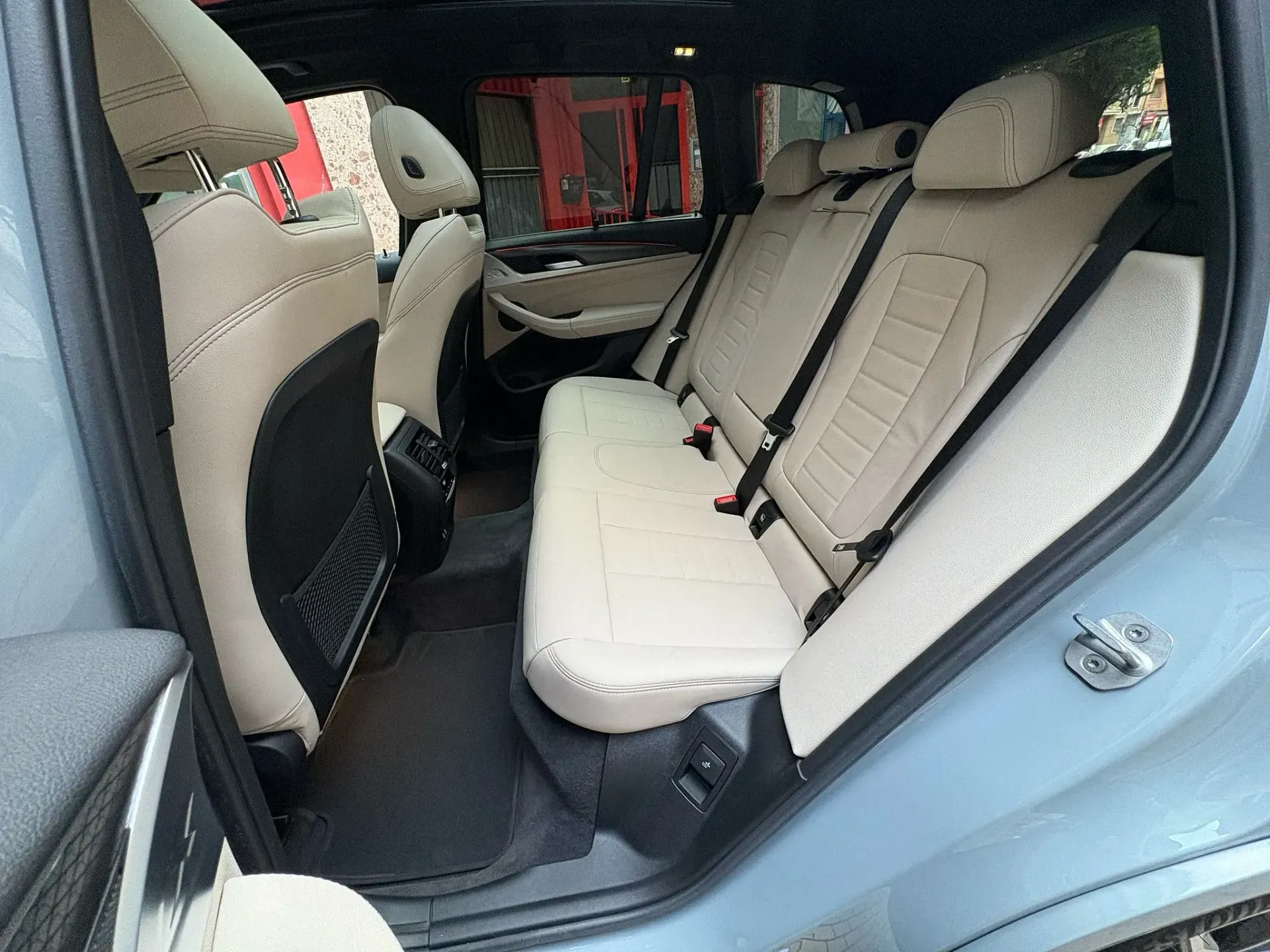 Se muestra el asiento trasero de un automóvil con la puerta abierta.