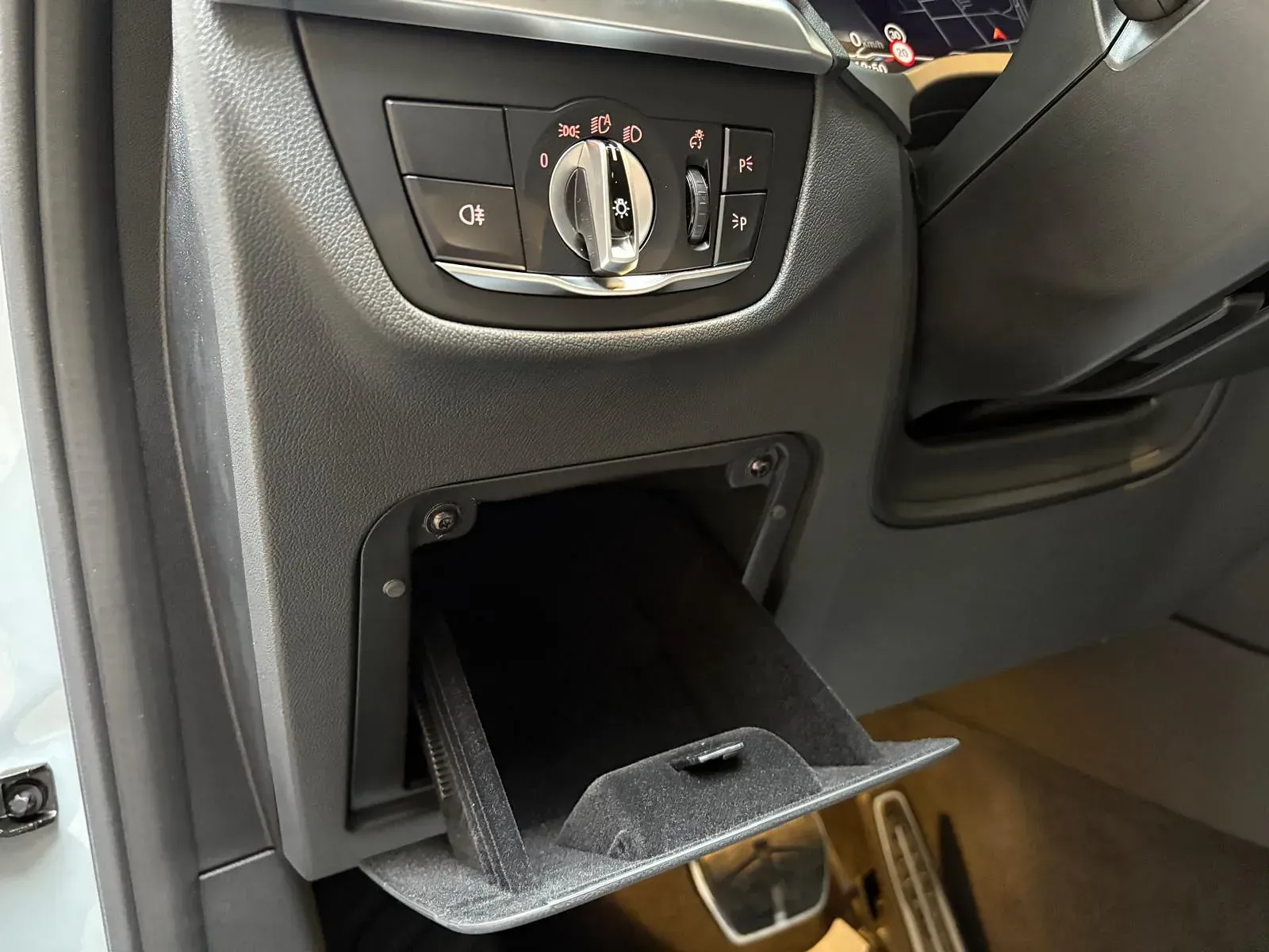 Un primer plano del salpicadero de un coche con la guantera abierta.