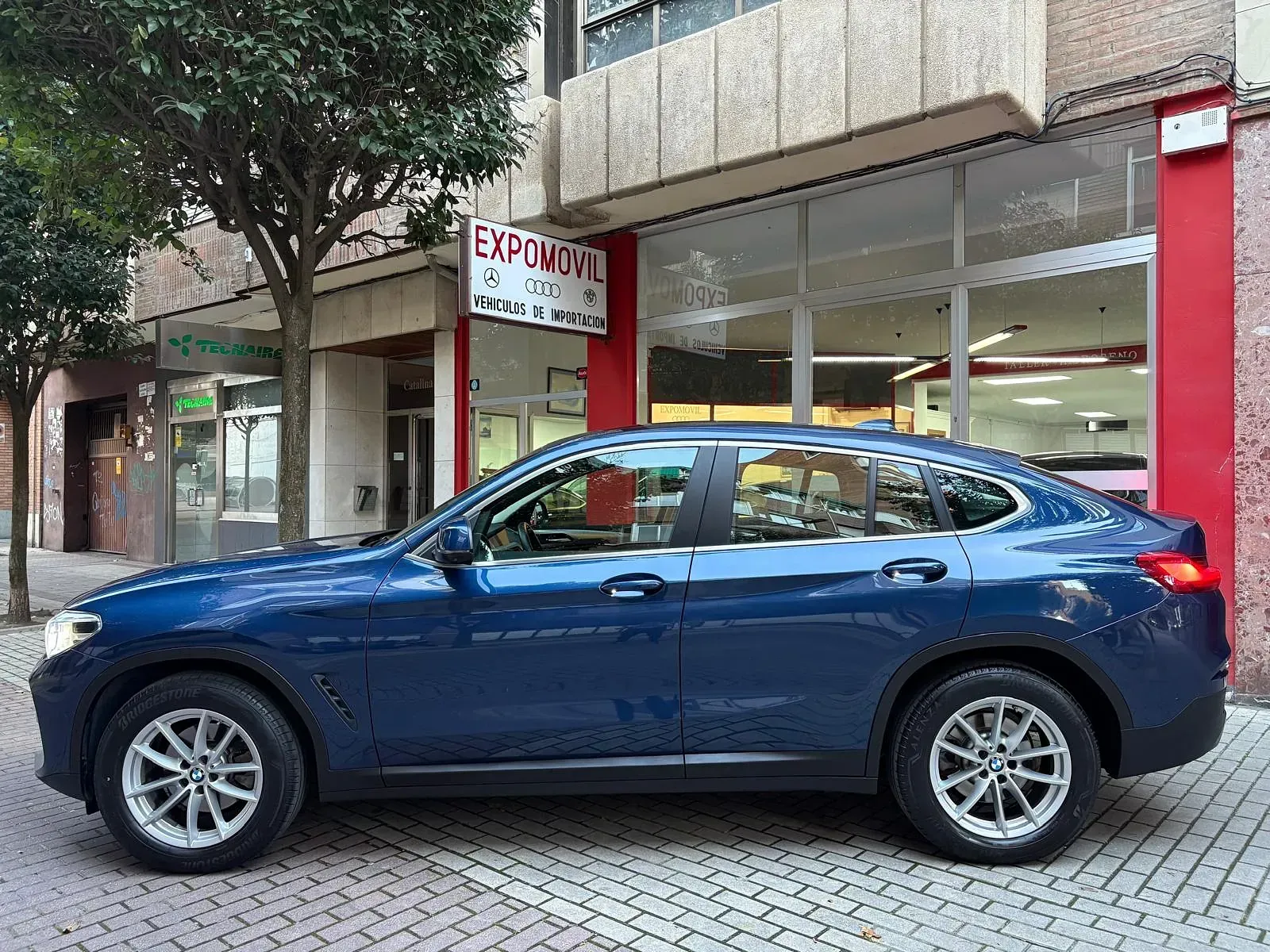 Un coche azul está aparcado delante de un concesionario de automóviles.