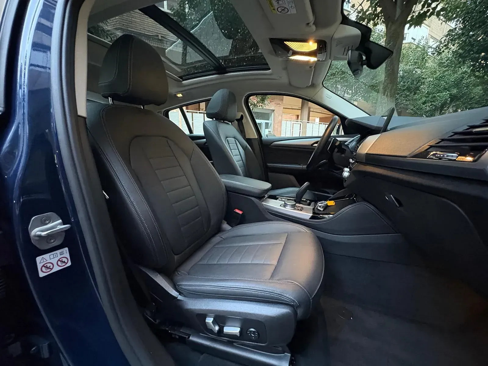 El interior de un coche azul con el techo corredizo abierto.