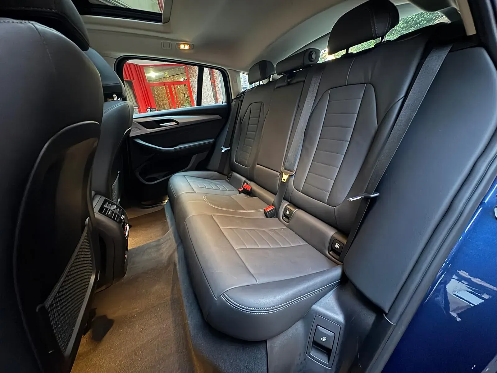 El asiento trasero de un coche azul con techo corredizo.