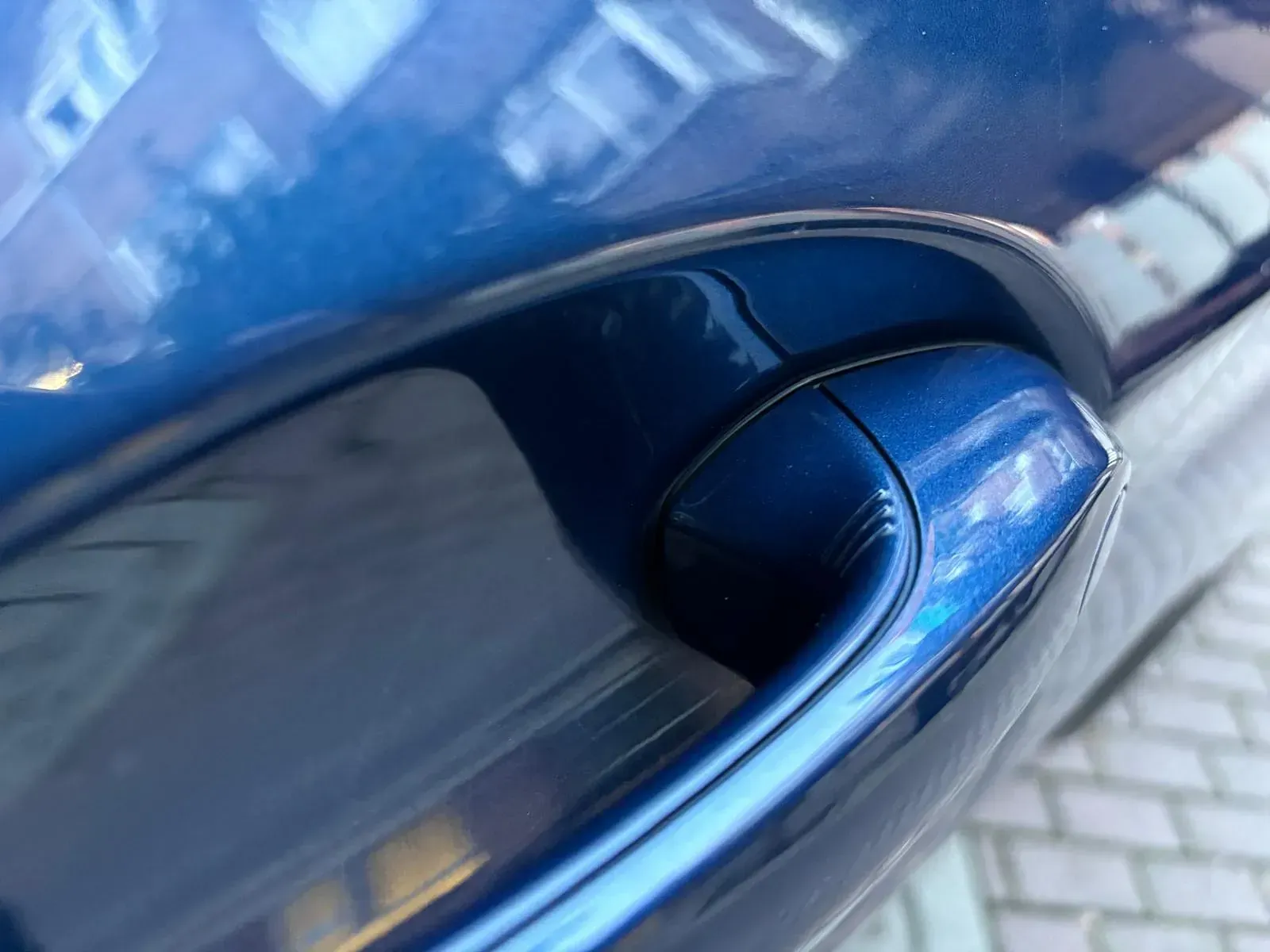 Un primer plano de la manija de la puerta de un automóvil azul.