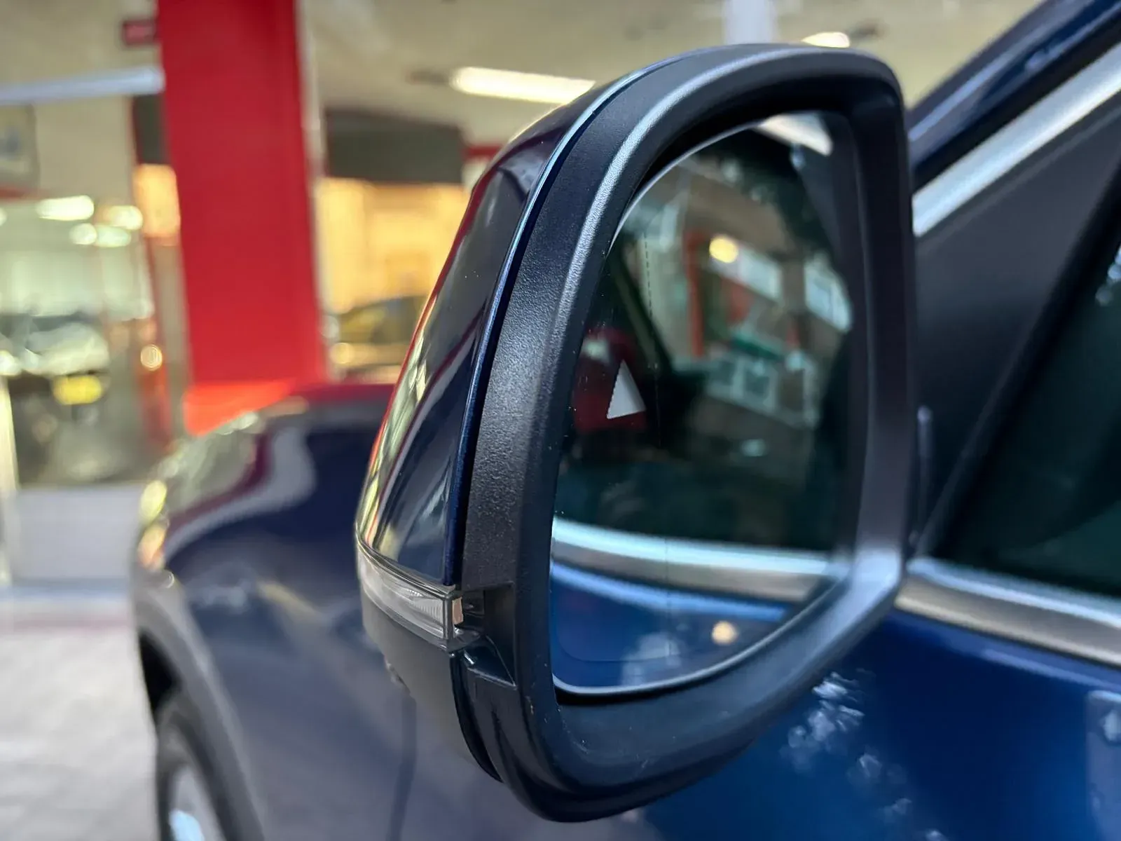 Un primer plano de un espejo retrovisor lateral de un automóvil azul.