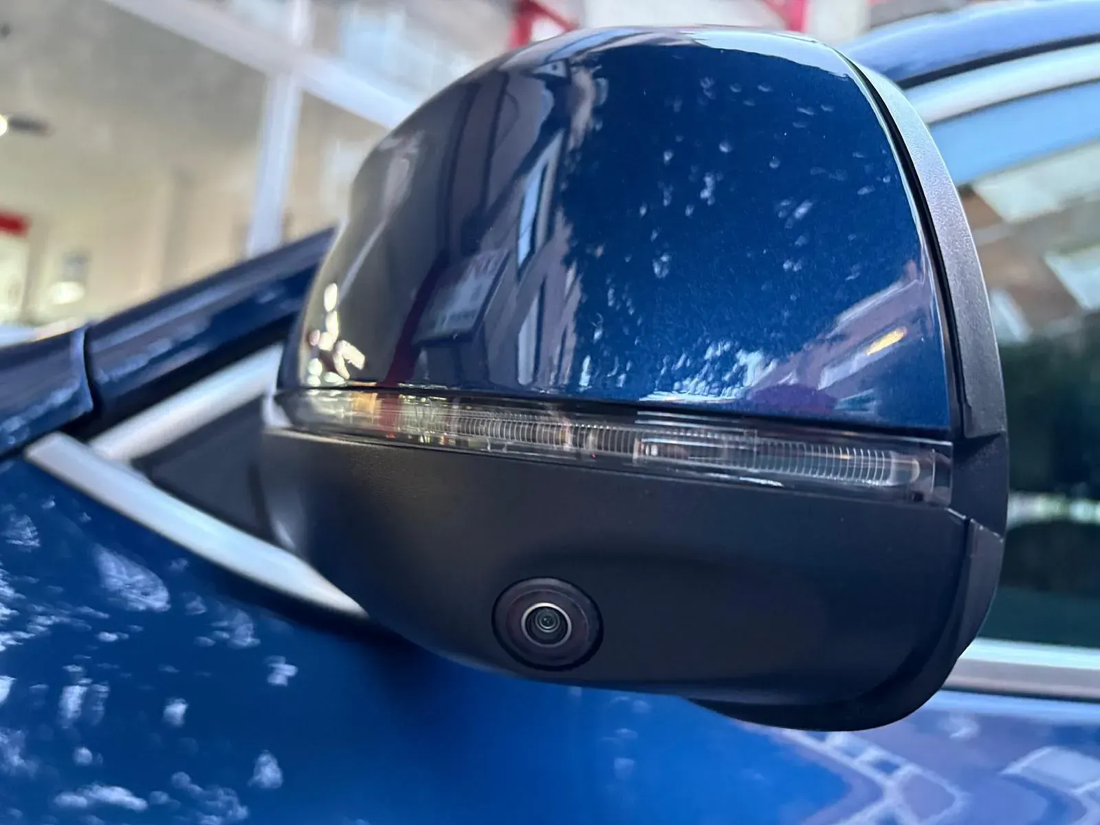 Un primer plano de un espejo retrovisor lateral de un automóvil azul.