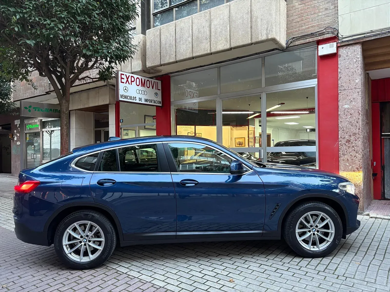 Un coche azul está aparcado delante de un edificio.