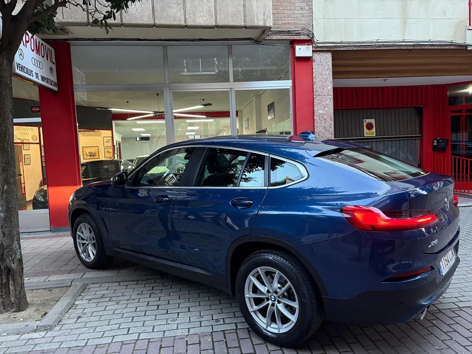 Un coche azul está aparcado delante de un edificio.