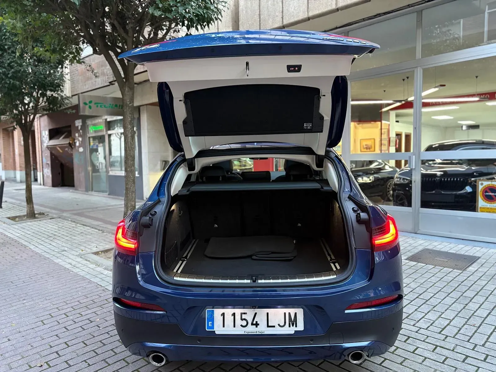 La parte trasera de un coche azul con el maletero abierto.