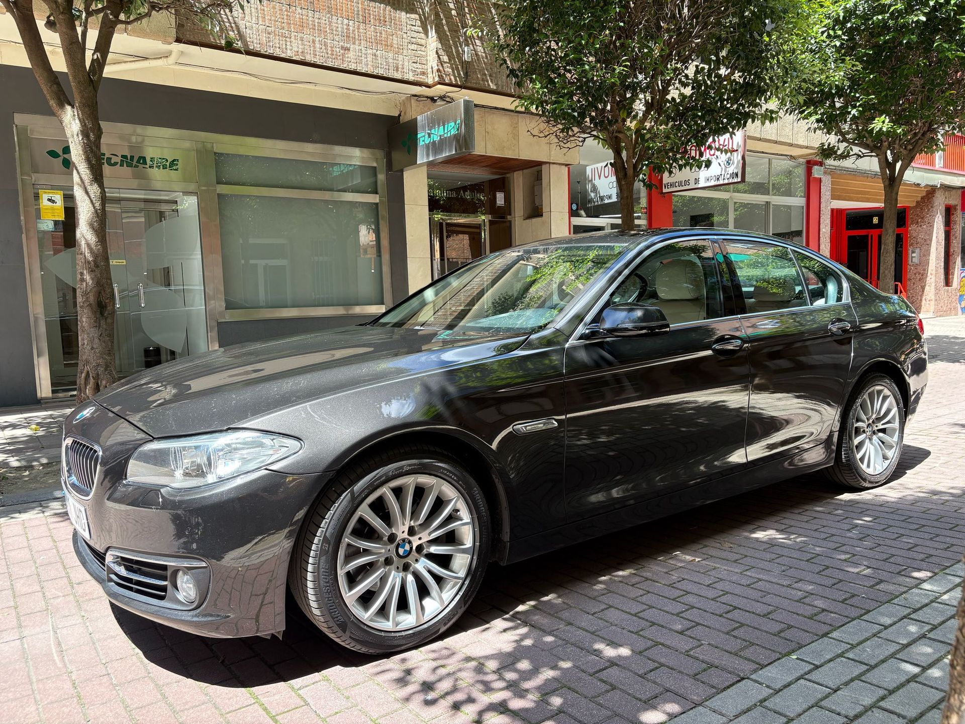 Un coche negro está estacionado al costado de la carretera frente a un edificio.