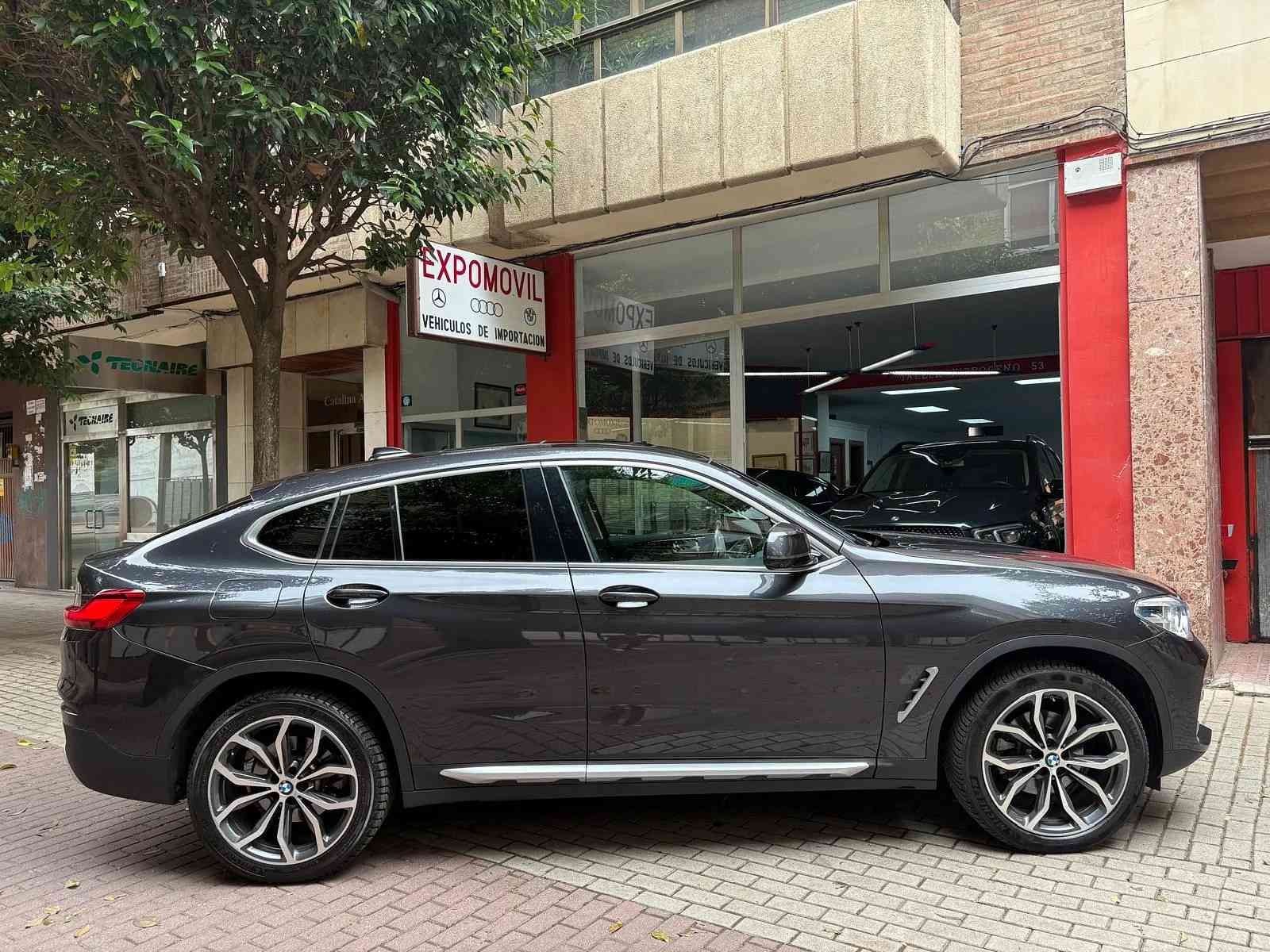 Un BMW X4 está estacionado frente a un concesionario de automóviles.