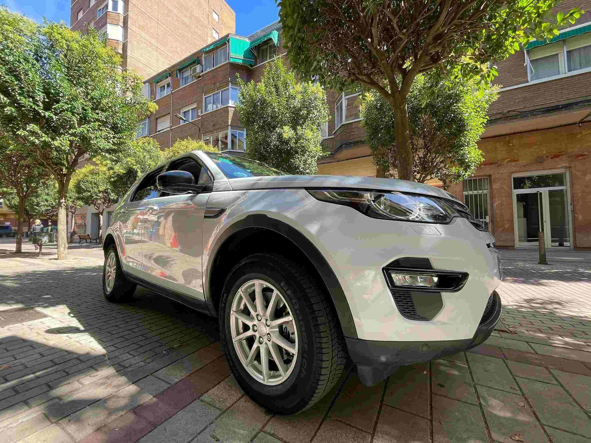 Un coche blanco está estacionado en una acera frente a un edificio.